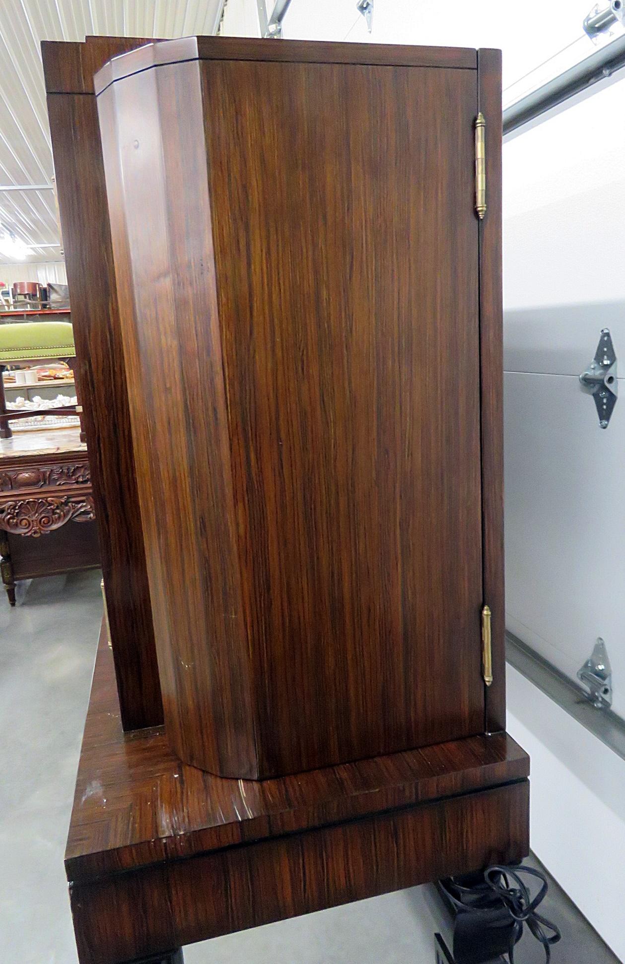 Art Deco style rosewood bar with ebonized legs and accents. Each side door holds 1 glass shelf. The centre doors contain 2 glass shelves.