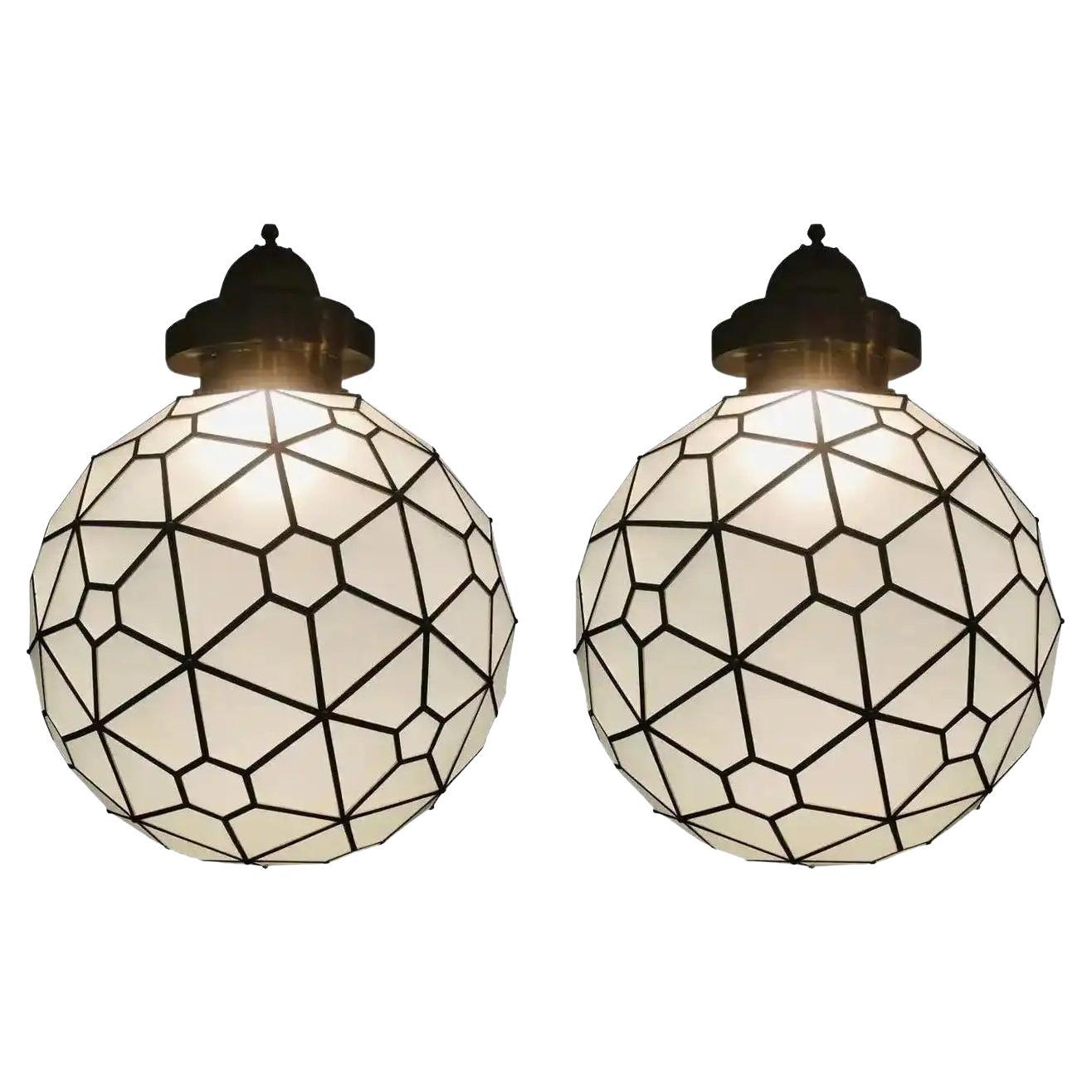 An exceptional and stunning pair of Art Deco style milk glass round shape chandeliers or pendants with brass inlay and handcrafted with a filigree design canopy. These fine custom lanterns or pendants are rare and very chic. They will elevate the