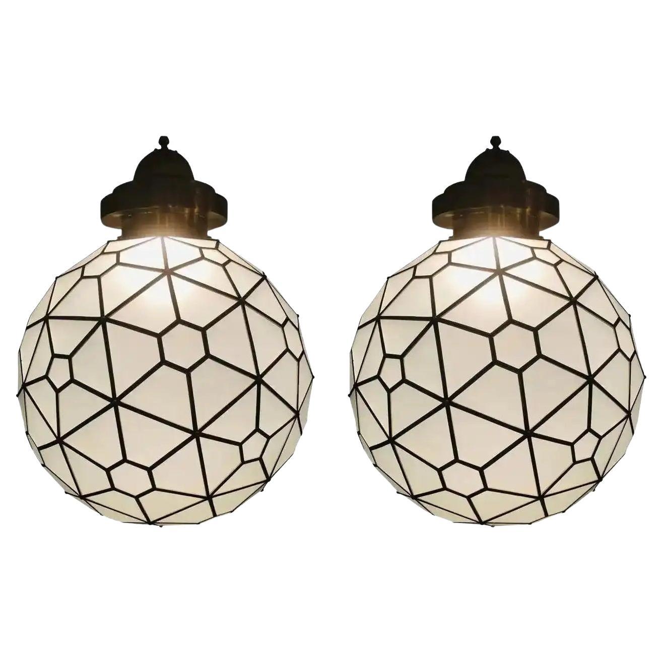 Un'eccezionale e straordinaria coppia di lampadari o pendenti in vetro lattimo in stile Art Déco, con intarsi in ottone e realizzati a mano con un baldacchino dal design a filigrana. Queste raffinate lanterne o ciondoli personalizzati sono rari e