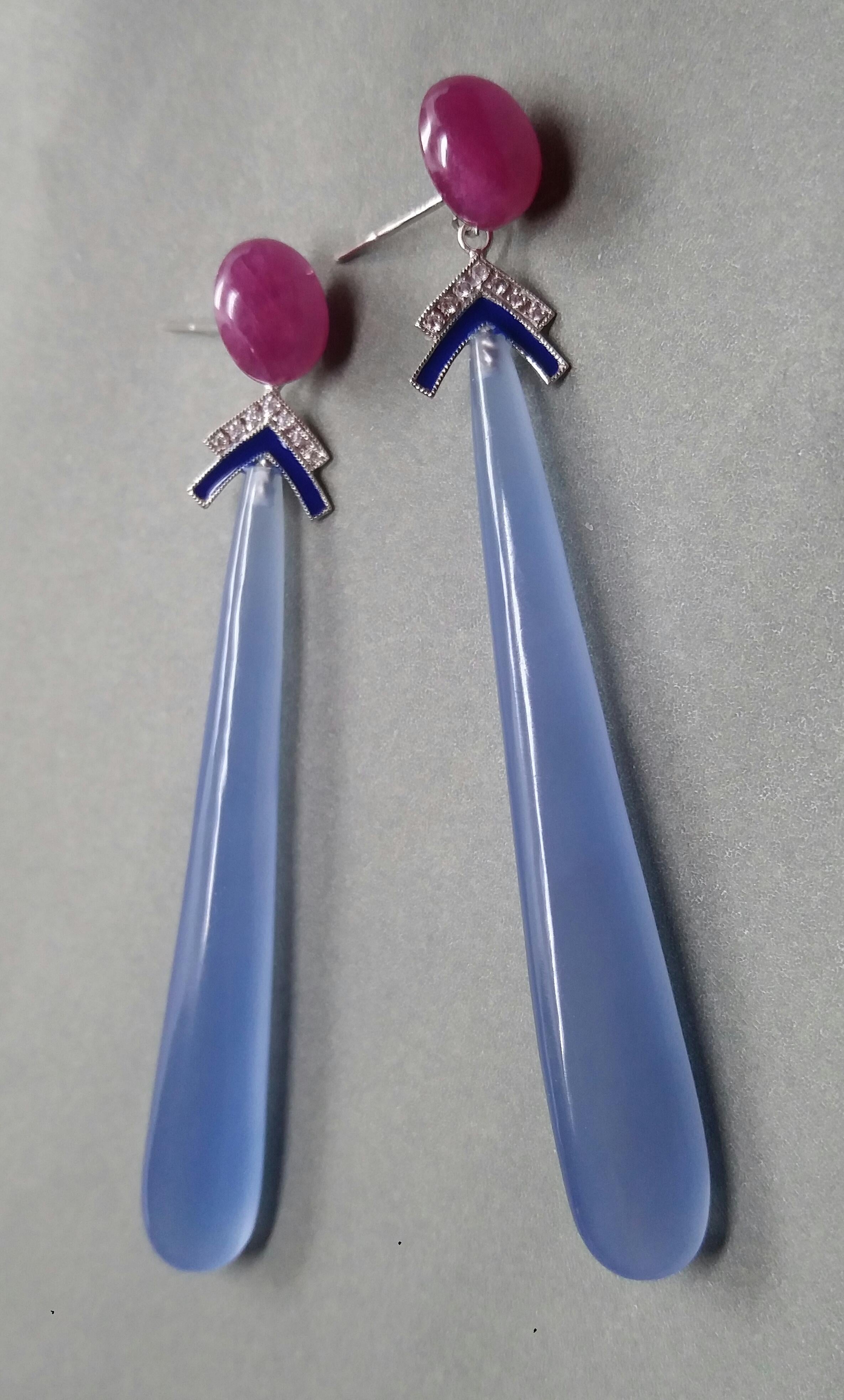 Ces boucles d'oreilles classiques de style Art déco comportent deux cabochons ovales en rubis, puis deux éléments en or blanc avec diamants et émail bleu  à laquelle sont suspendues 2 longues gouttes d'agate bleue

En 1978, notre atelier a démarré