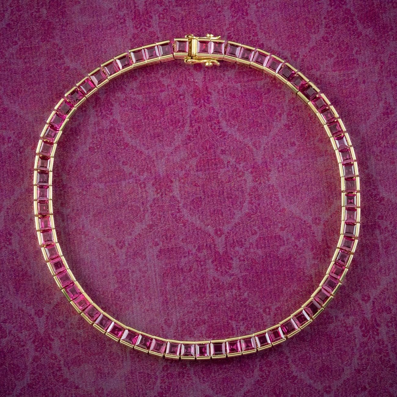 A glamorous Art Deco inspired tennis bracelet showcasing sixty-five square cut rubies with a deep cherry-pink hue. Each is tension set in an 18ct gold setting and weigh approx. 0.10ct each, making a grand total of approx. 6.5ct. Made Circa