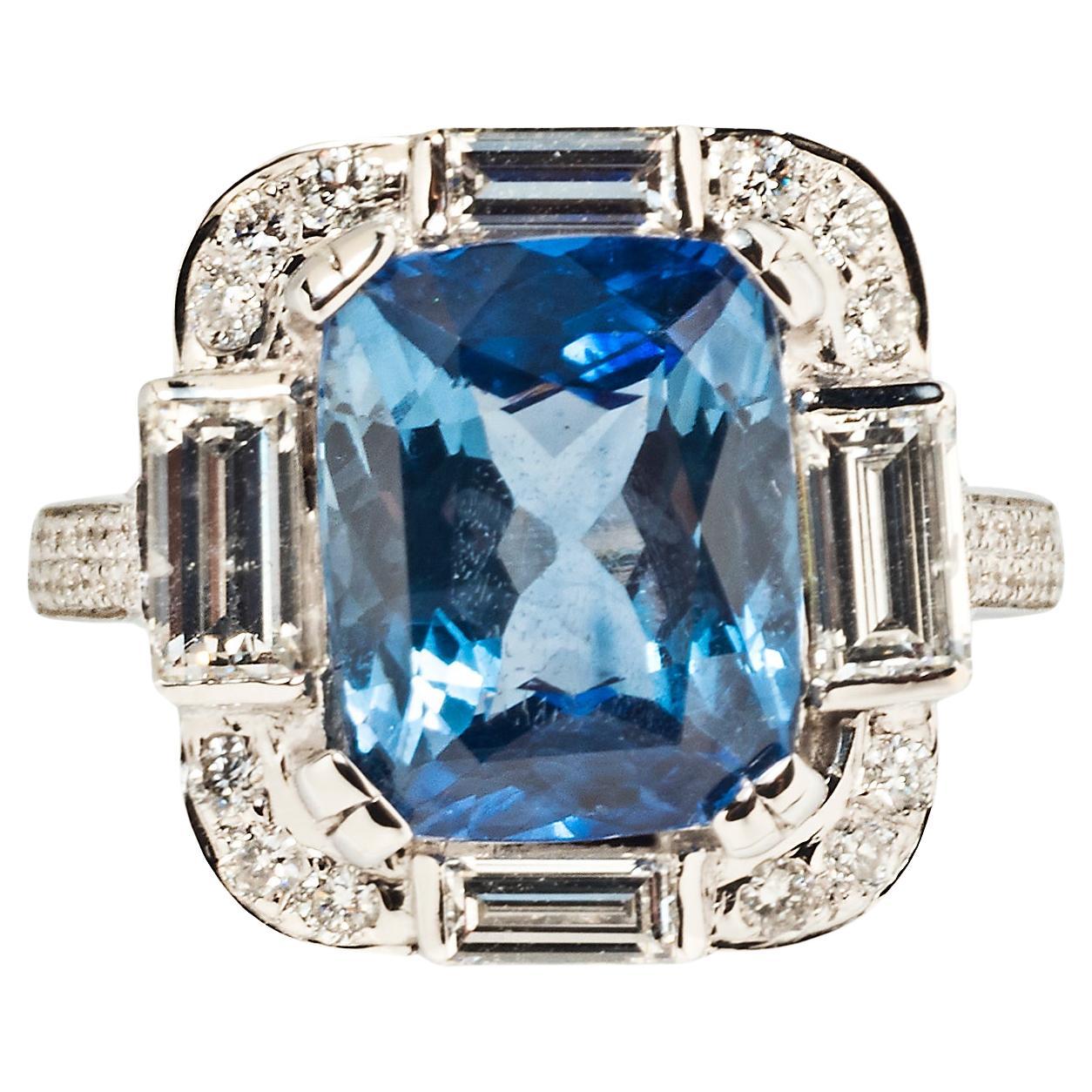 A dramatic cocktail ring in the Art Deco style centers on a cushion cut sapphire surrounded by four rectangular step-cut diamonds. Each corner is set with a full-cut melee and the shoulder shank is pavé-set with 98 full-cut melee.

Accompanied by