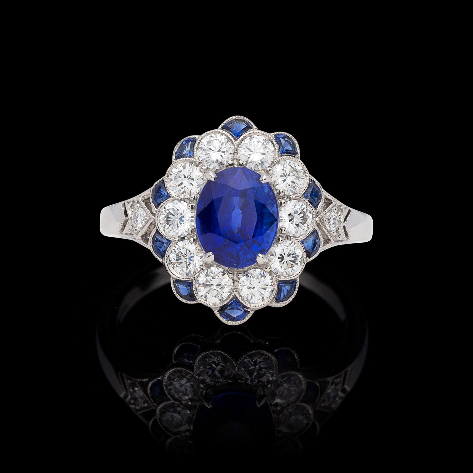 A beautiful update on the classic Lady Diana ring, this platinum Art Deco inspired ring centers an oval-shaped sapphire weighing approximately 1.65 carats, with well saturated, deep blue color, surrounded by sparkling round brilliant-cut diamonds