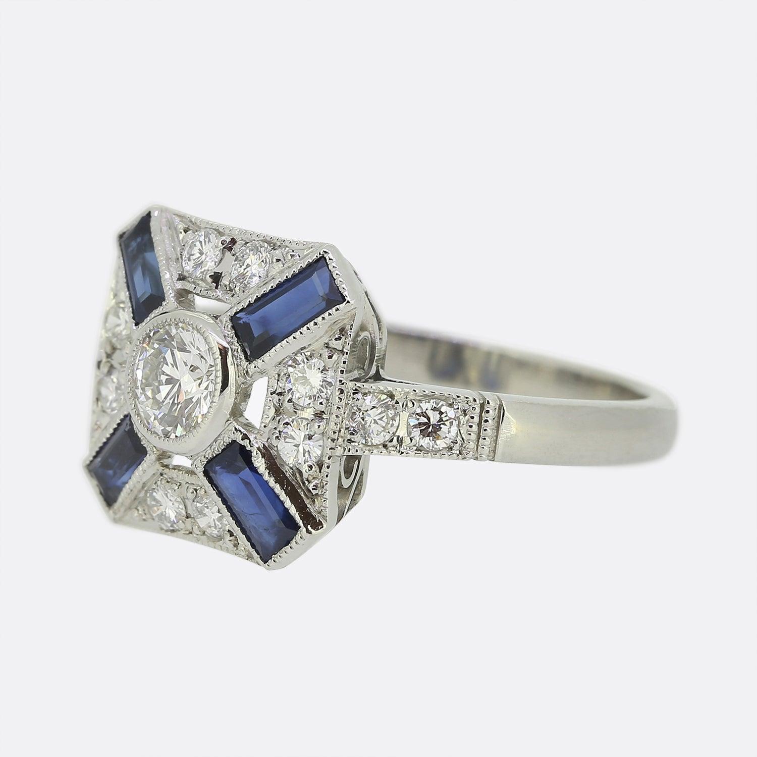 Here we have a delightful sapphire and diamond target ring. This piece borrows from a classic Art Deco style with a square shaped head playing host to a centralised, bright white round brilliant cut diamond. This principle stone is then accompanied