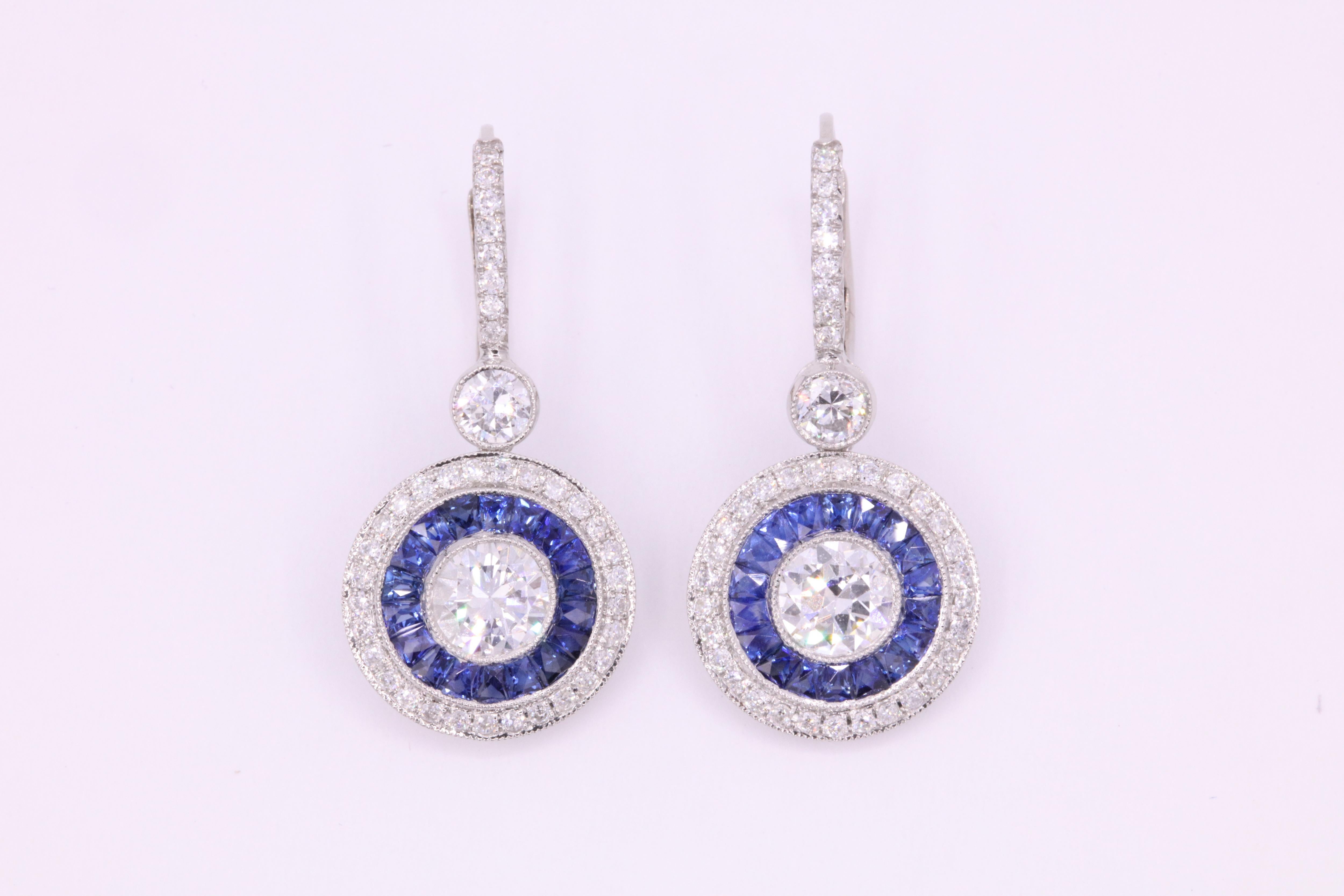 Art Deco inspired earrings featuring 2 round brilliants weighing 1.67 carats flanked with vibrant blue sapphires, 1.53 carats and diamonds 0.95 carats, crafted in platinum.