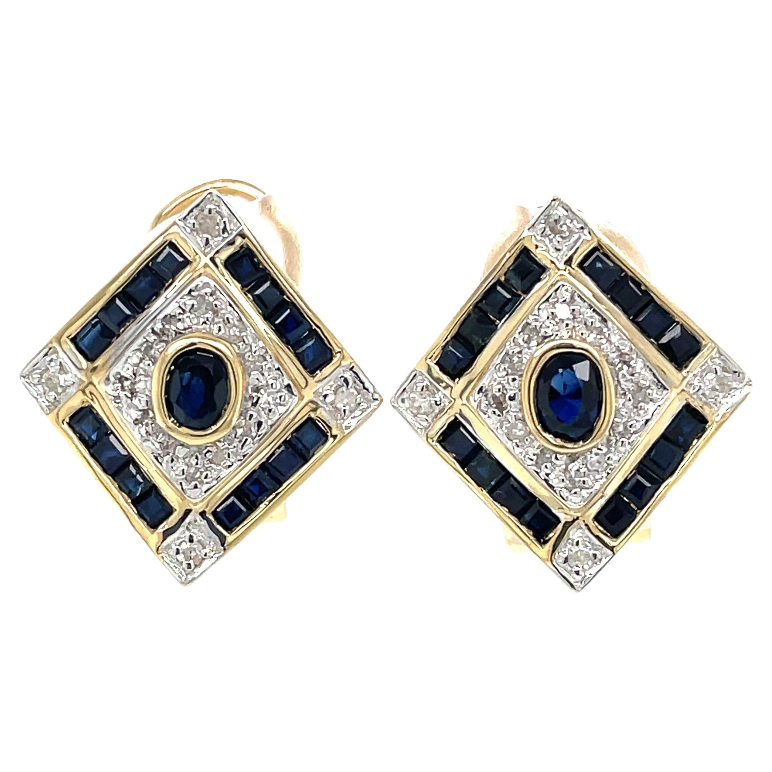In Art Deco style, this attractive 14 karat yellow gold earring pair's design has center set blue round sapphire bezel set and framed by matching square cut sapphires, .64 TW.  Adding light to this regal pair, are small diamonds accents, .24 TW