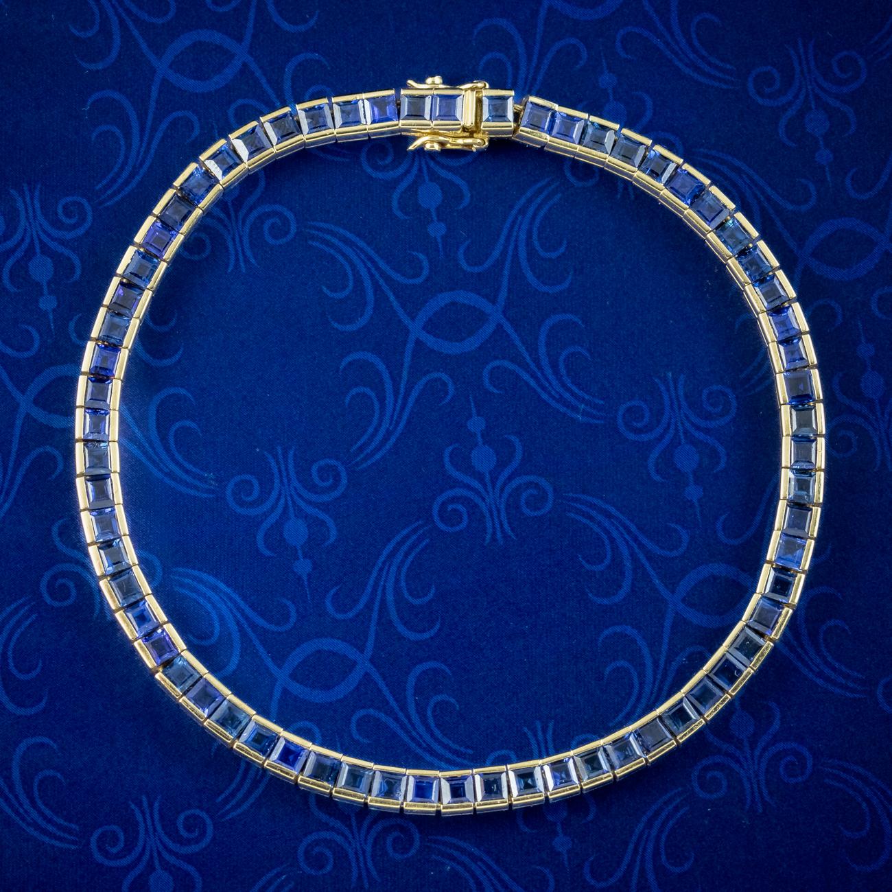 A glamorous Art Deco inspired tennis bracelet showcasing sixty-five square cut sapphires with a deep Bristol-blue hue. Each is tension set in an 18ct gold setting and weigh approx. 0.10ct each, making a grand total of approx. 6.5ct. Made Circa