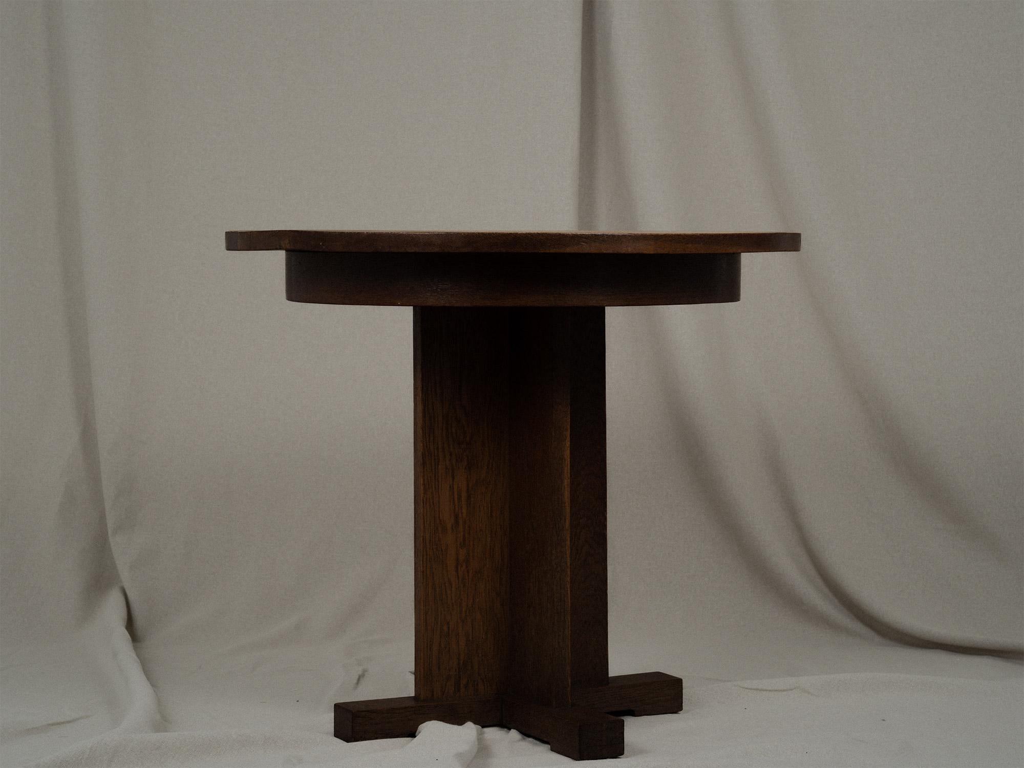 Sculptural round wooden side or accent table in the style of Art Deco. The sleek cross-shaped base and feet with heavy solid table top gives this piece a refined and modern appearance. In good vintage condition, the wear is consistent with age and