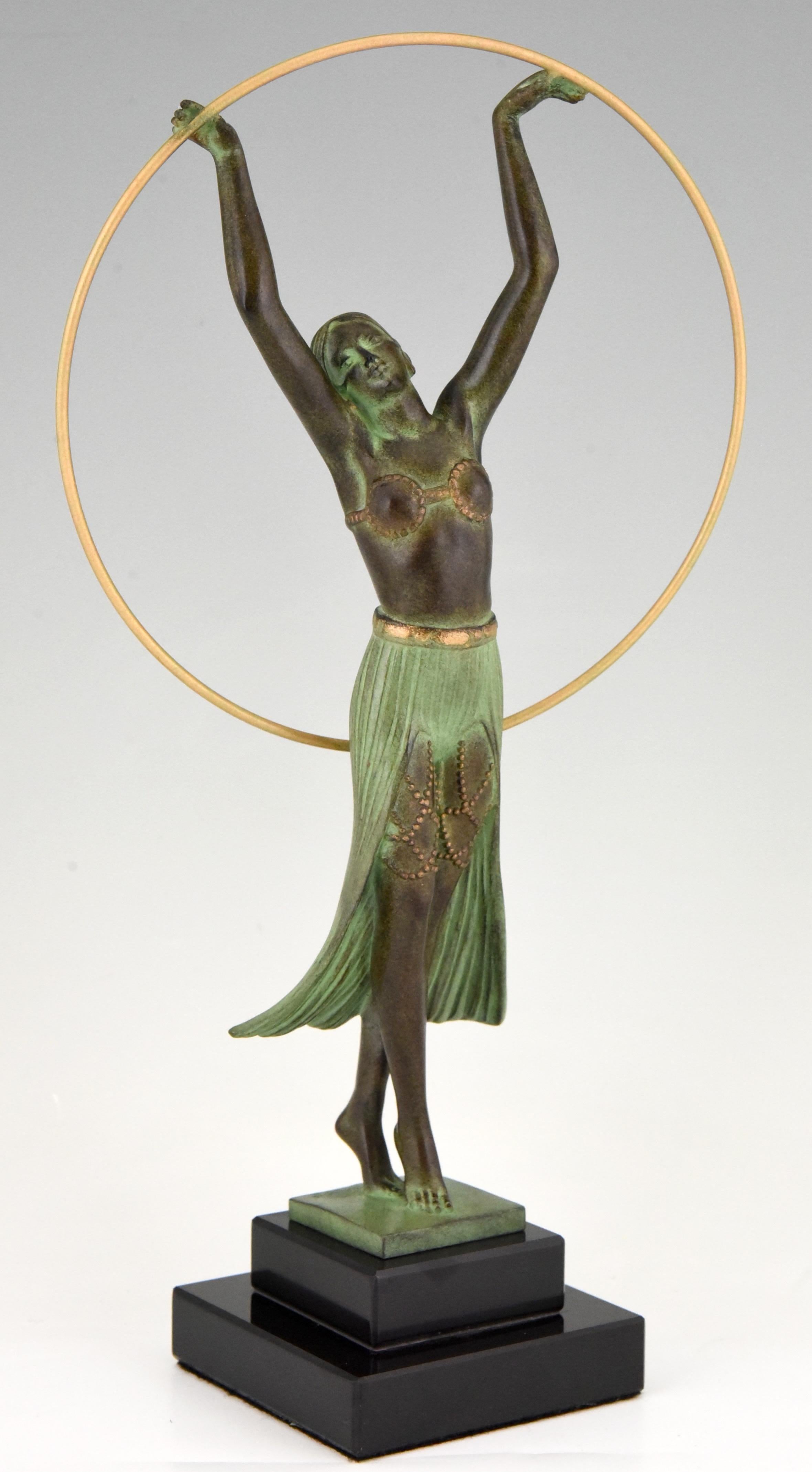 Elegante Skulptur einer Frau mit Reifen im Art Deco Style, signiert von dem französischen Künstler C. Charles, gegossen in der Gießerei Max Le Verrier.
Die Metallskulptur hat eine schöne grüne Patina und steht auf einem Sockel aus schwarzem Marmor,