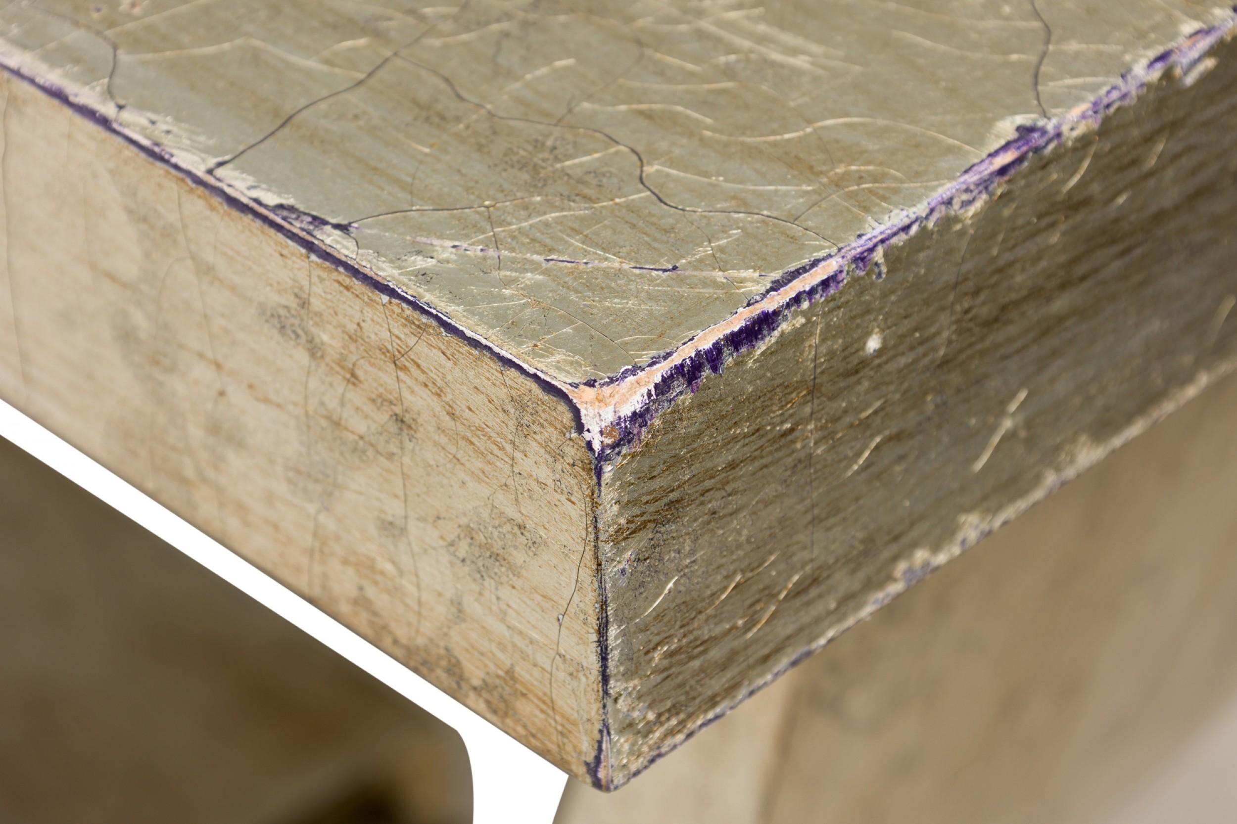 Art Deco-style rectangular wooden console table with curved supports anchored in a rectangular stepped base, finished in a crackled gilded silver.

Some damage to finish, lower joints are very loose