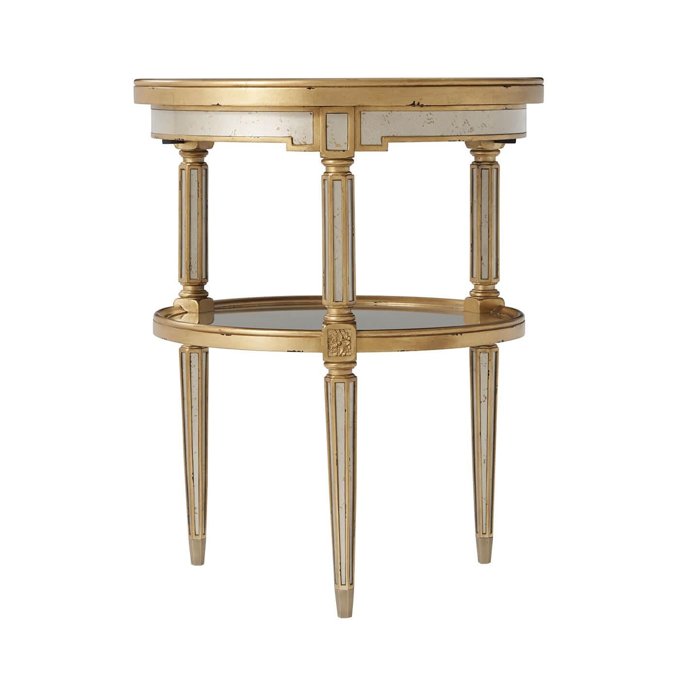 An Art Deco style silvered and gilt verre Eglomise two-tier circular table, the dished and molded edge top above a similar under tier, joined by octagonal section supports, on tapering legs. 

Dimensions: 23