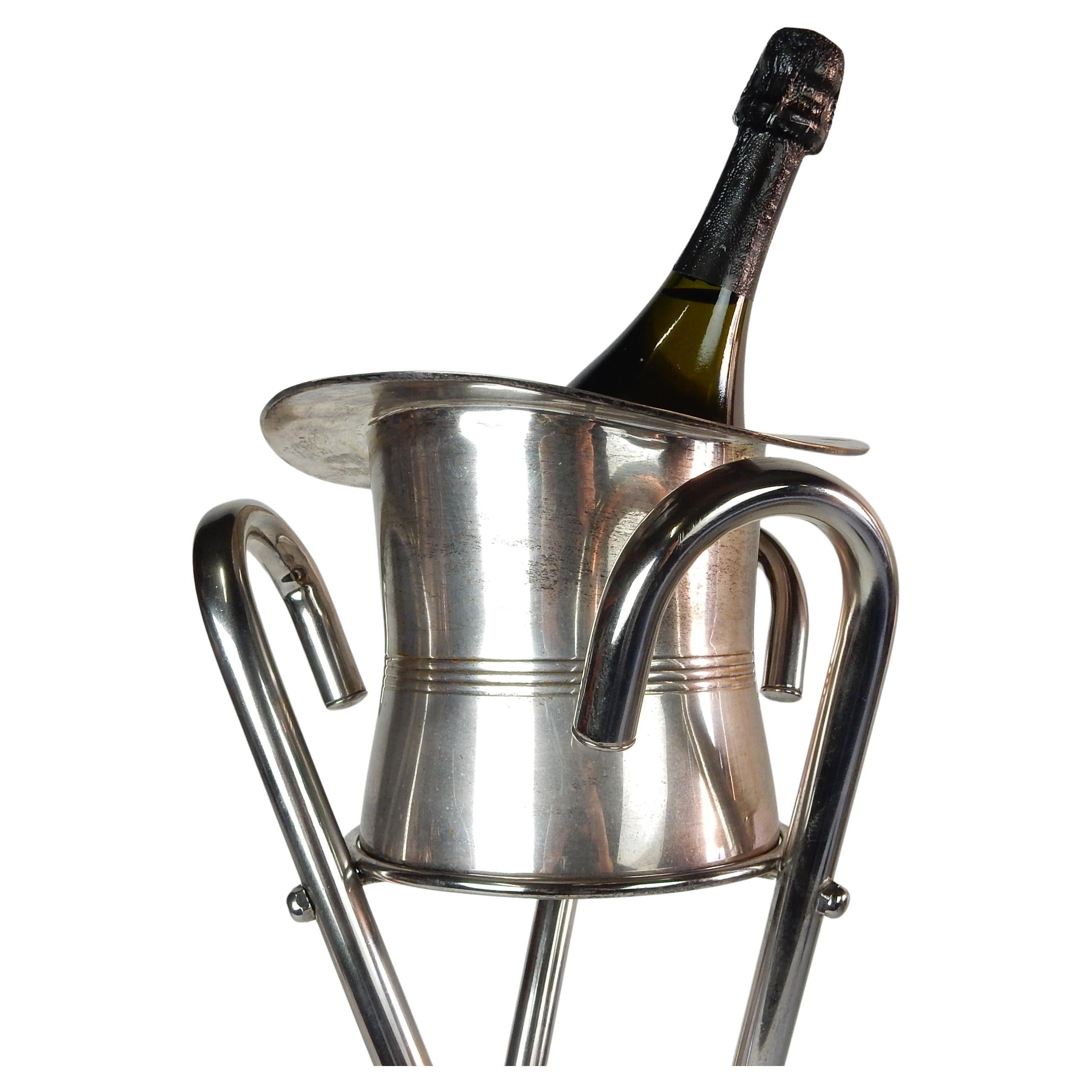 Circa 1970's silver plated champagne ice bucket in the shape of a gentlemen's top hat on a tripod walking cane stand.
From the fashion house of 