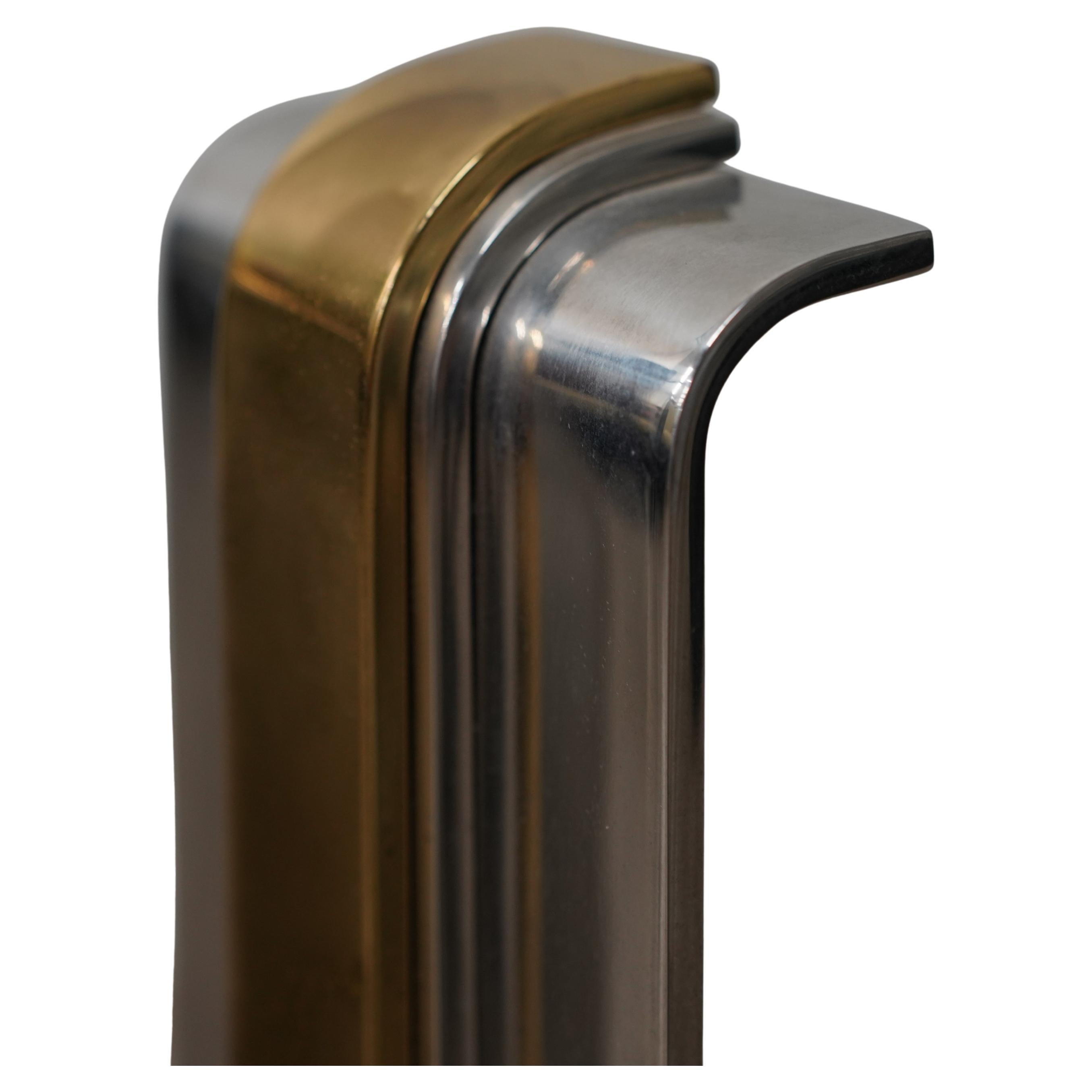 A striking pair of Art Deco style polished steel and brass andirons, designed by Danny Alessandro, circa 1984. The meticulously crafted and very luxurious andirons feature a modernist, stepped streamlined design with an inverted curve at the top of