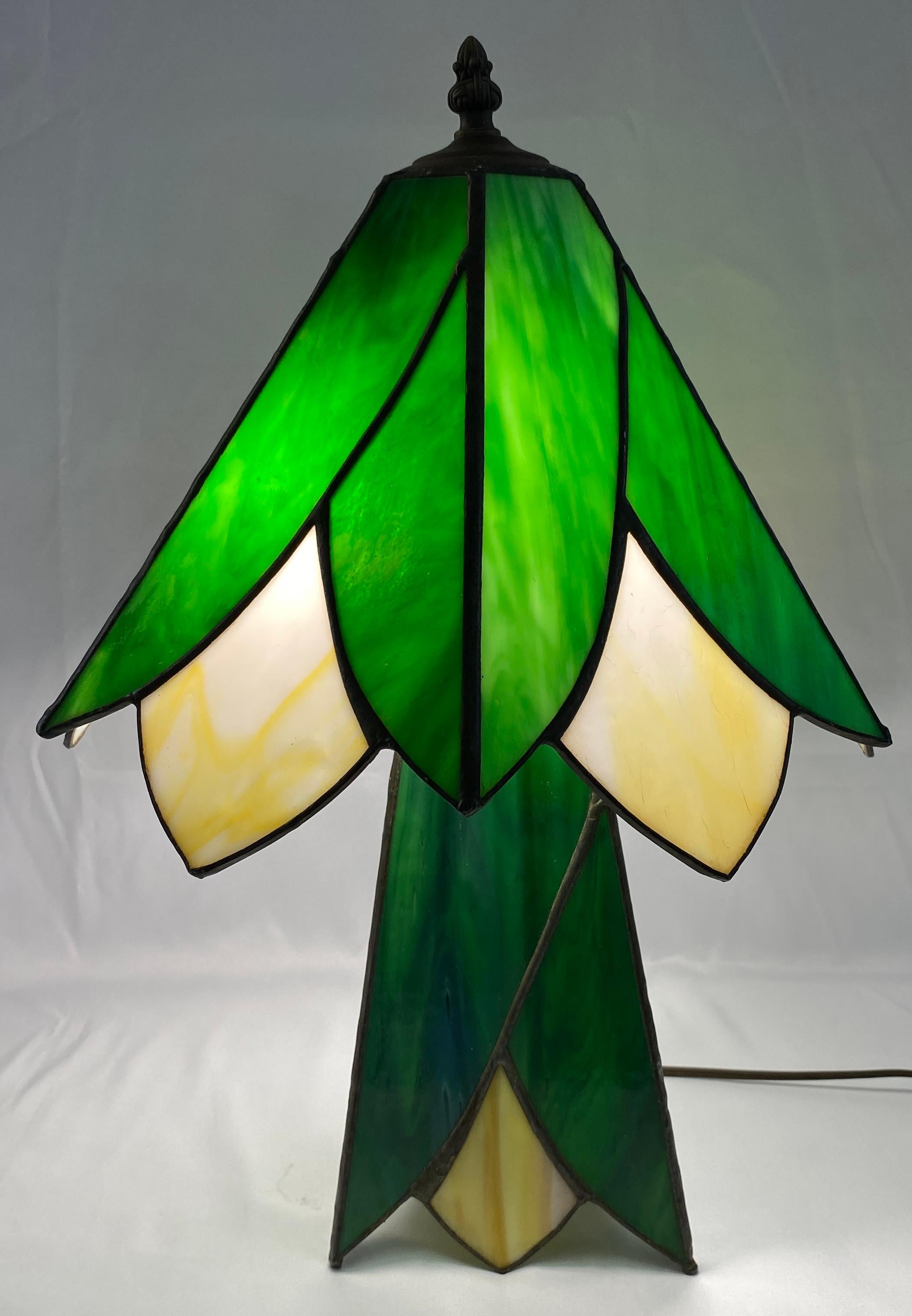 Unveil the mystery of this captivating Art Deco style table lamp!  This rare design, with its unknown origins, exudes the unmistakable elegance of the era.  The lamp has striking features including the stained glass panels and a unique base design. 