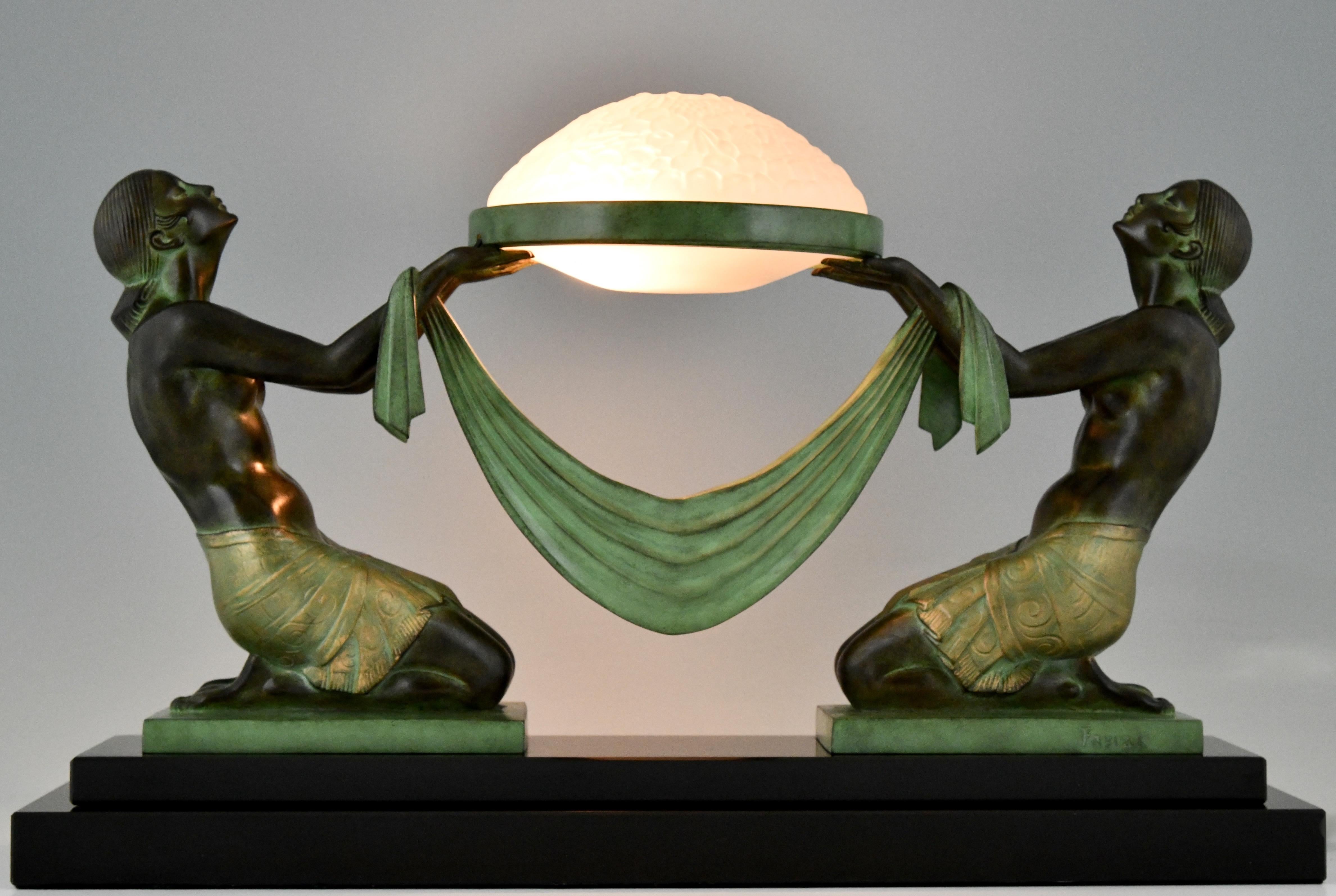 Art Deco style lamp with kneeling nudes holding a glass shade Offrande signed Fayral, pseudonym of Pierre Le Faguays cast at the Max Le Verrier foundry. 
Design Ca. 1925.
Patinated Art metal. Glass shade. Black marble base. 
Posthumous contemporary