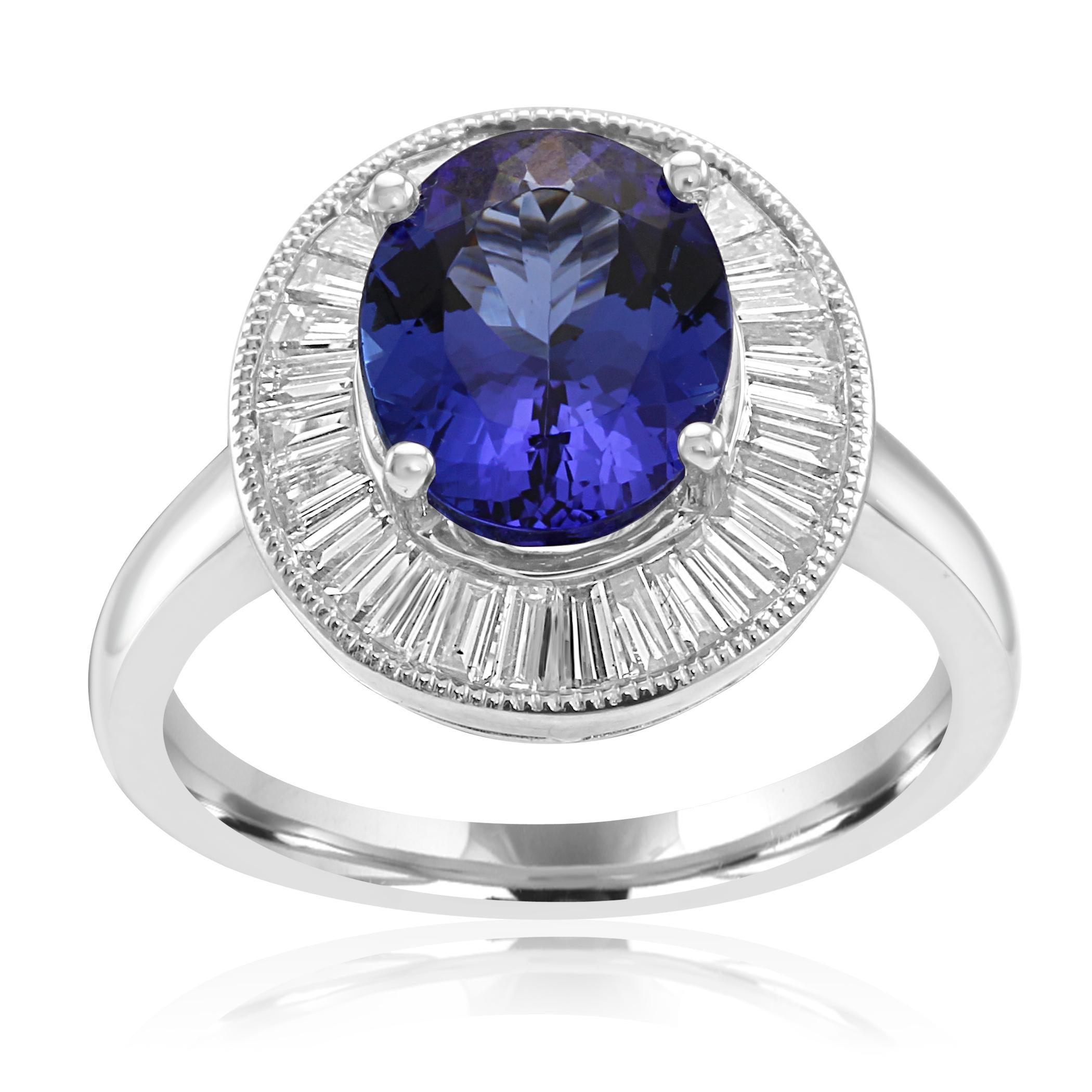 Stunning Art Deco Style Tanzanite Oval 2.77 Carat Encircled in a Single Halo of White G-H Color VS Clarity Diamond Baguette 0.80 Carat with nice filigree work on the side in 18K White Gold Bridal Fashion Cocktail Ring. Total Weight 3.57