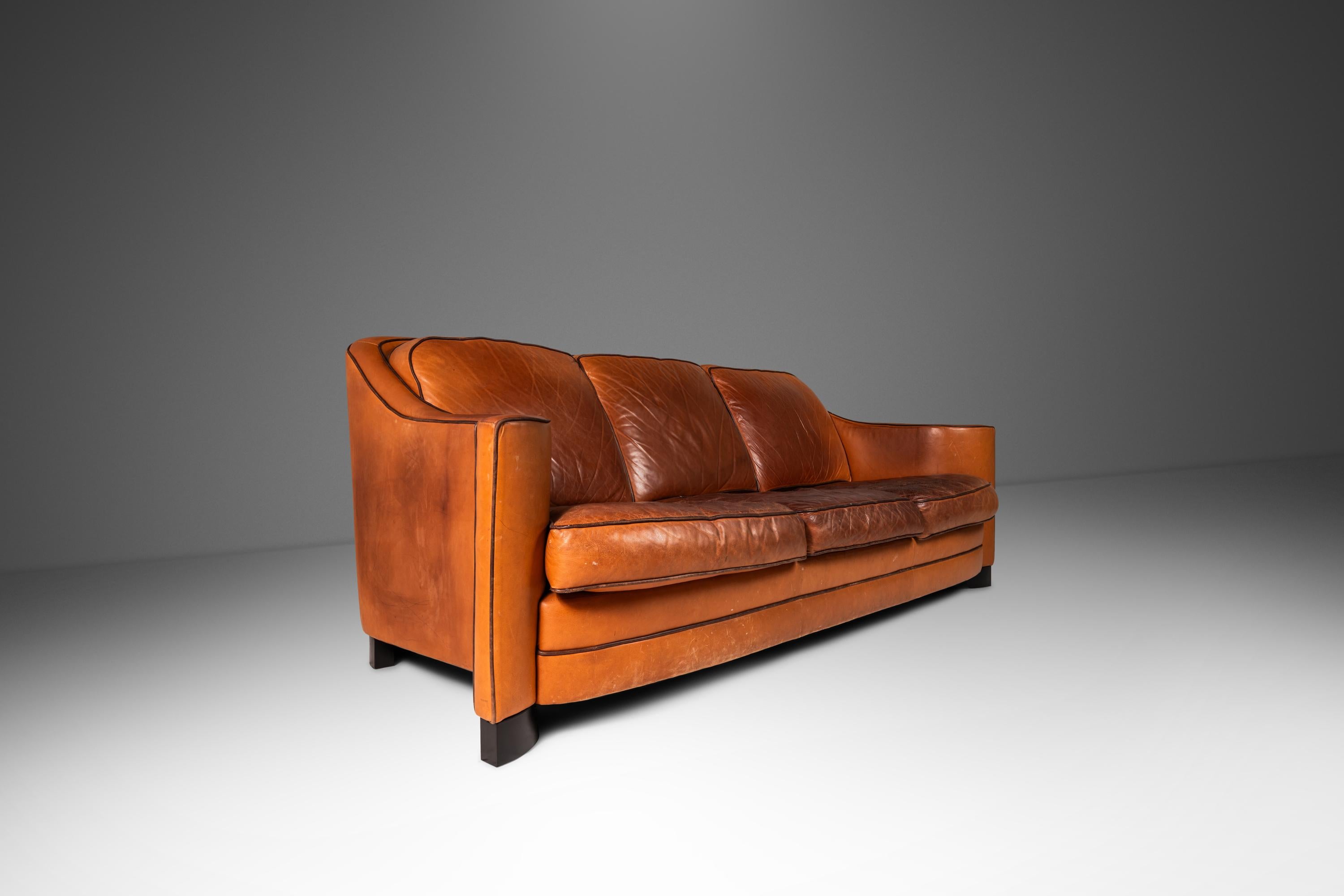 Architettonicamente stupefacente e ultra-confortevole, questo divano a tre posti eccezionalmente elegante ha molto da offrire a designer e collezionisti. Con braccioli scolpiti di ispirazione art-decò e piedi curvi intricatamente intagliati, questo