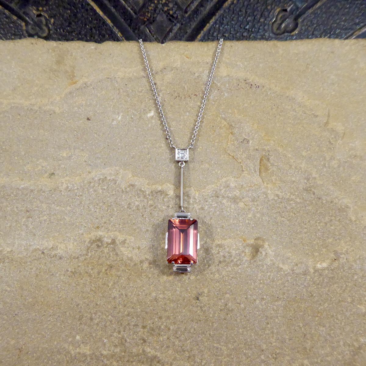 This lovely contemporary necklace has been hand crafted in an Art Deco style. The necklace features a Emerald Cut Red Tourmaline with Baguette Cut Diamonds on the top and bottom of the gemstone, this hangs on a straight bar with a Diamond Bail to