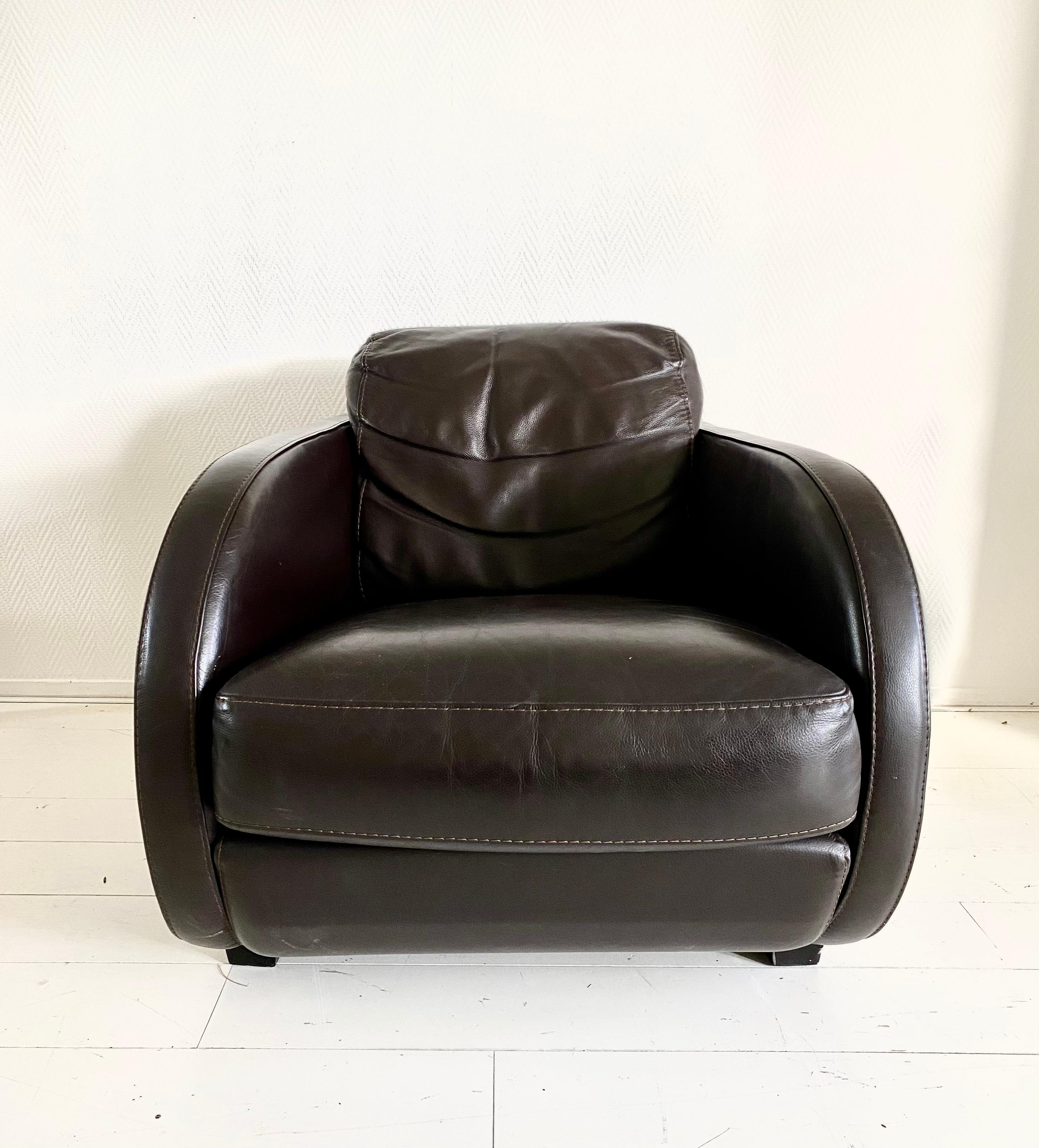 This exclusive lounge fauteuil was manufactured by Roche Bobois. It features a thick Brown leather upholstery, offers a highly comfortable seat and shows a typical Art Deco look. The chair remains in very good condition with some signs of age and