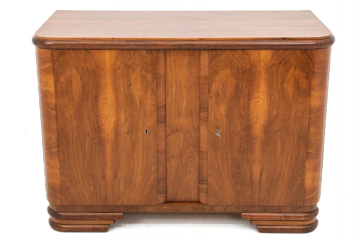Art Deco style walnut chest of drawers from the 1950s. The piece of furniture has been renovated in our workshop and is in very good condition. Walnut wood with a semi-matt finish. Lockable chest of drawers.

Dimensions:

Height: 79cm

Width: