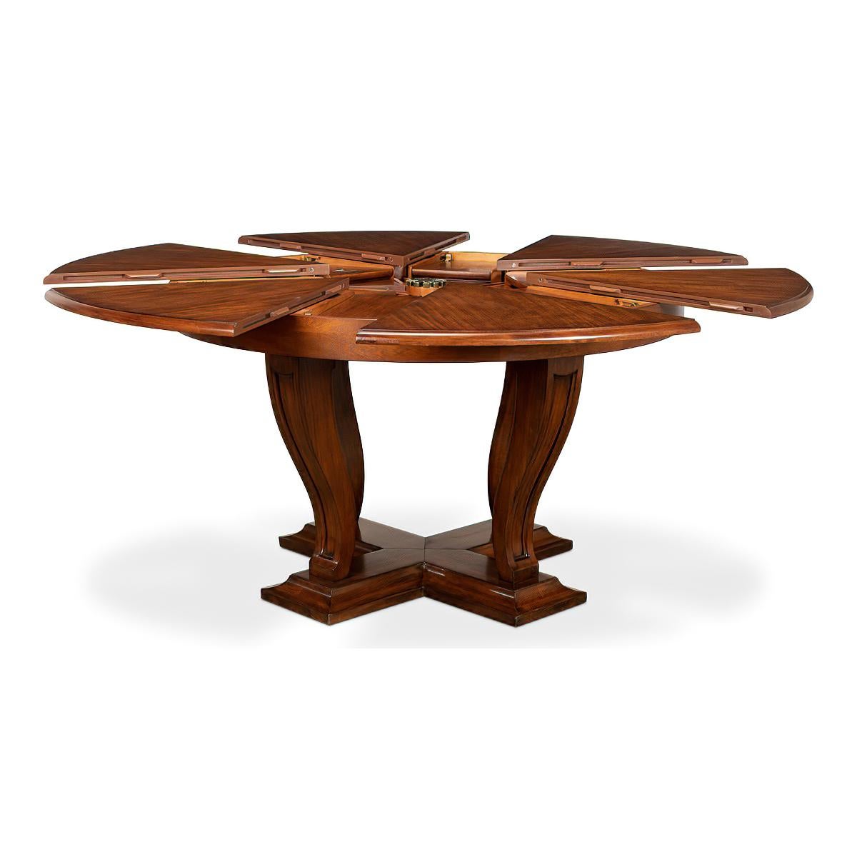 Art Deco Style walnut dining table on a transitional styled base consisting of tapered serpentine curved legs that have been carved with an inset panel design. They sit on a platform base that has been framed with a bold cove shape. The top is