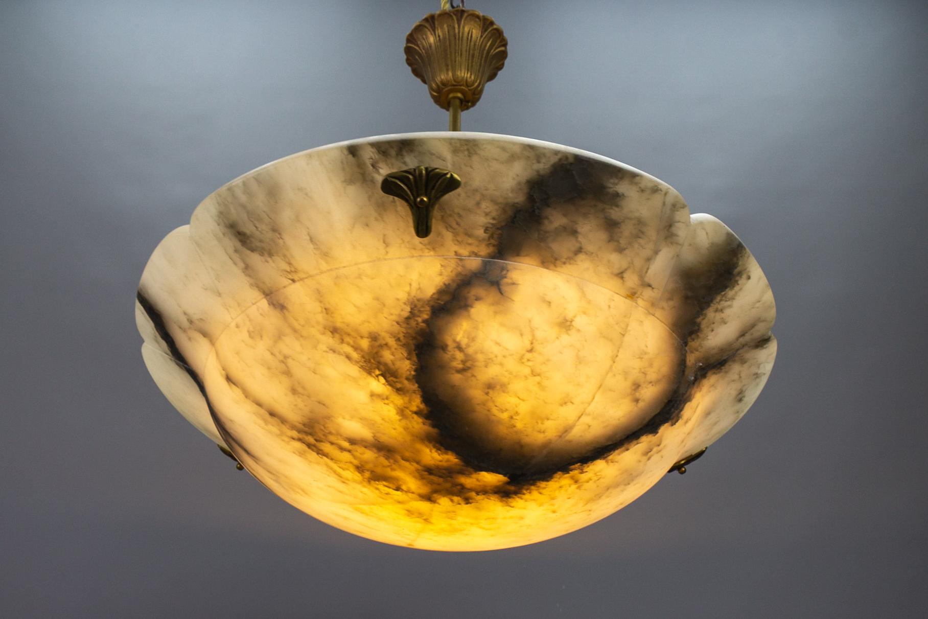 French Art Deco style black veined white alabaster pendant light fixture.
Gorgeous and beautifully shaped alabaster pendant ceiling light fixture from circa 1949. Superbly veined and masterfully carved white alabaster bowl suspended by three chains