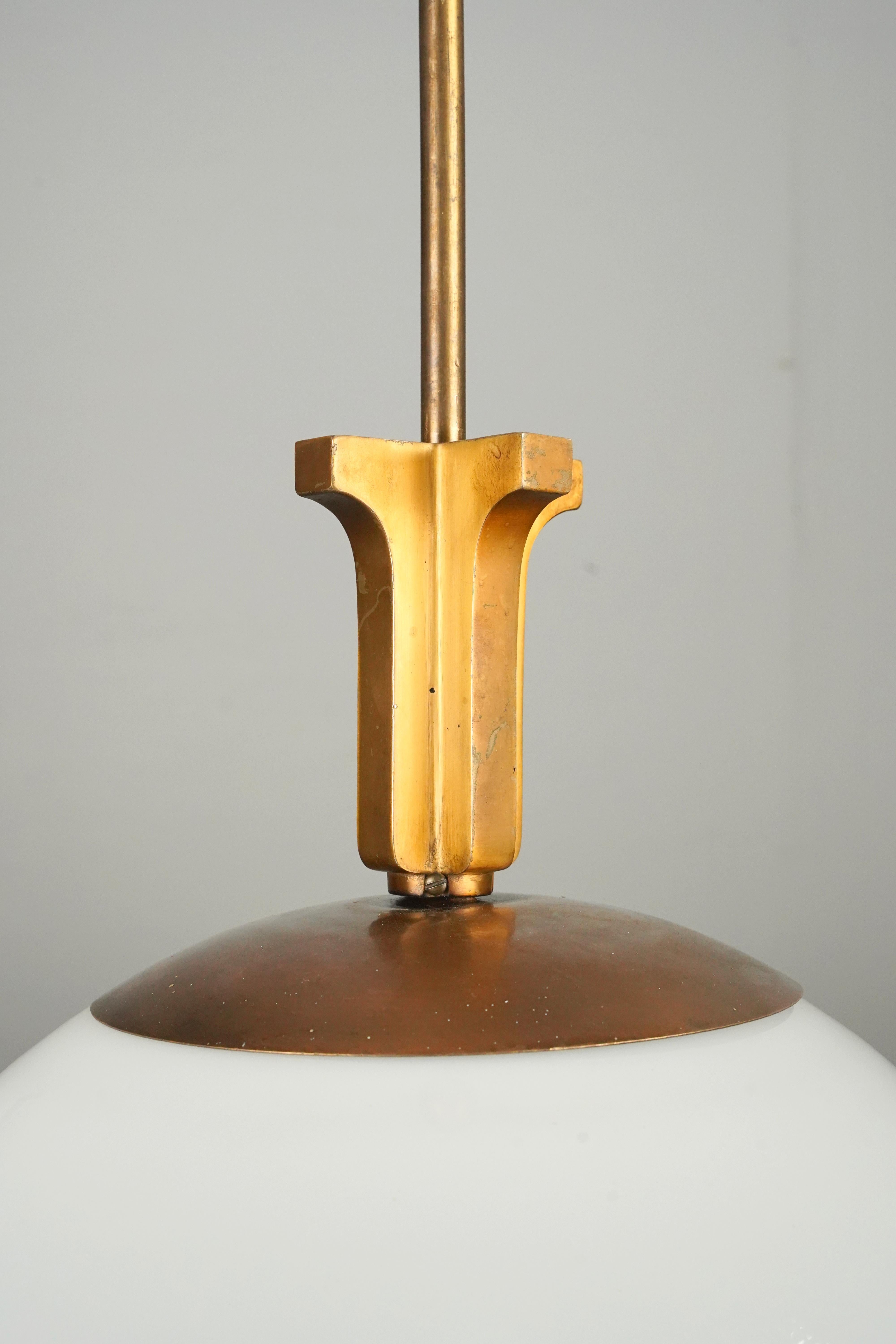 Lampada a sospensione in stile Art Déco con un globo di vetro bianco a forma di palla abbinato a un'asta in ottone spazzolato. Richiede una lampadina standard di tipo Edison a base media. Questa luce verrà pulita e restaurata prima della spedizione.