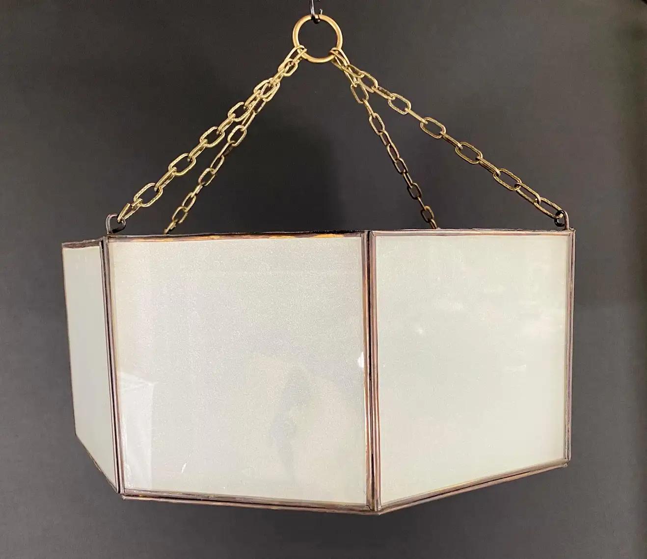 An Art Deco style pendant, lantern or flush mount. Featuring a stylish octagon shape, the pendant is finely hand-made of individual sandblasted frosted milk glass panels and patinated bronze frame. The octagonal shaped pendant has a small door on