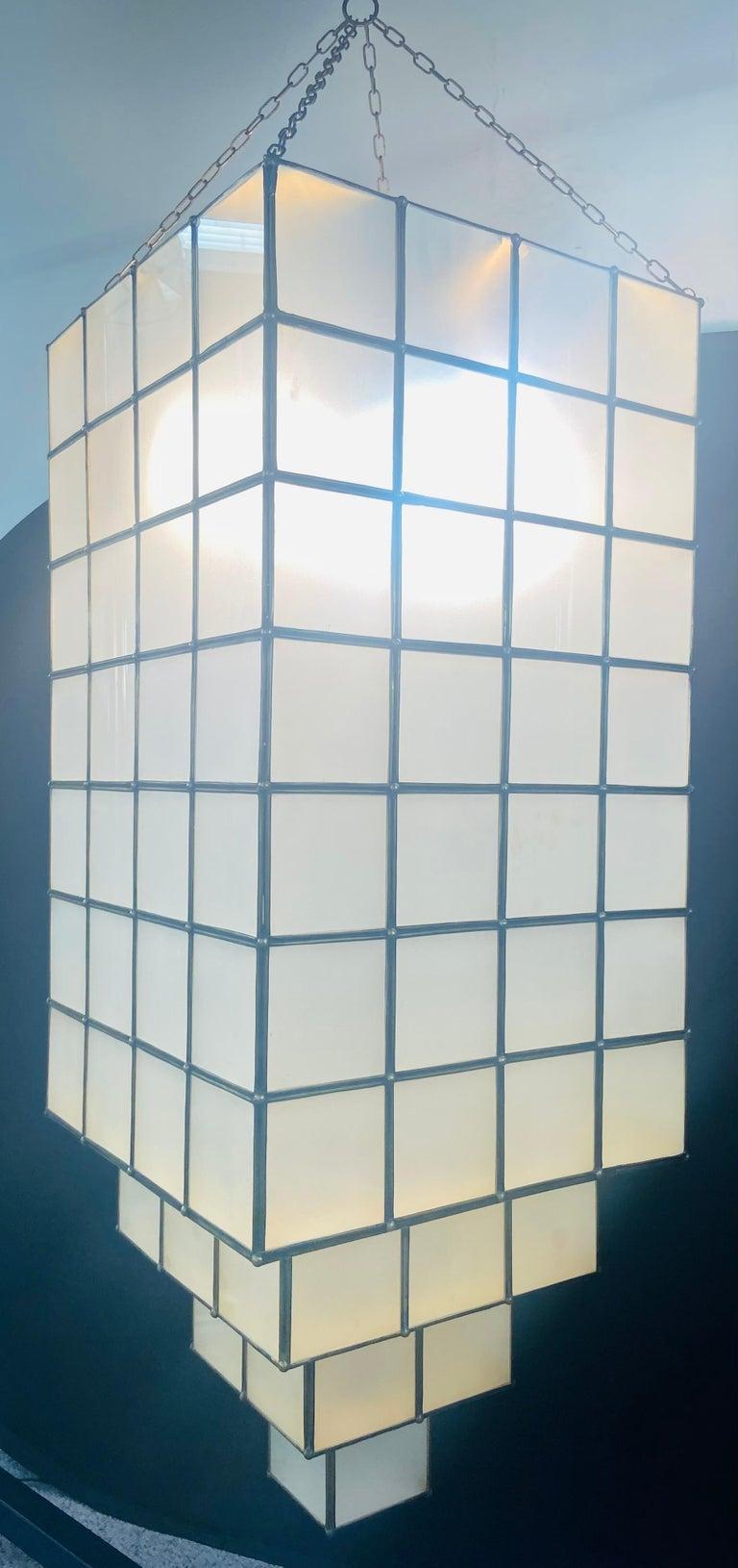 Light up your room with this stunning handmade pair of Art Deco style rectangular skyscraper design chandeliers or lanterns made of frosted white milk glass with fine brass frame. The chandeliers are built with square glass panels creating an