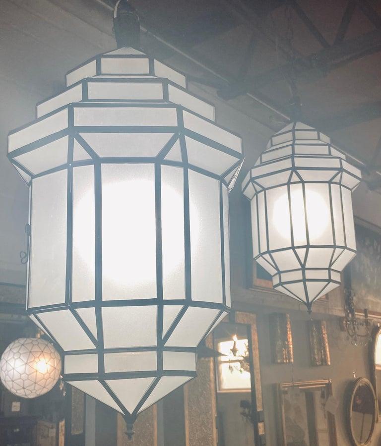 Art Deco style white milk glass handmade chandelier, pendant, lantern, a pair
A gorgeous handcrafted with individual panels, this pair of Art Deco hanging lanterns or ceiling fixtures features sandblasted frosted milky glass and patinated metal