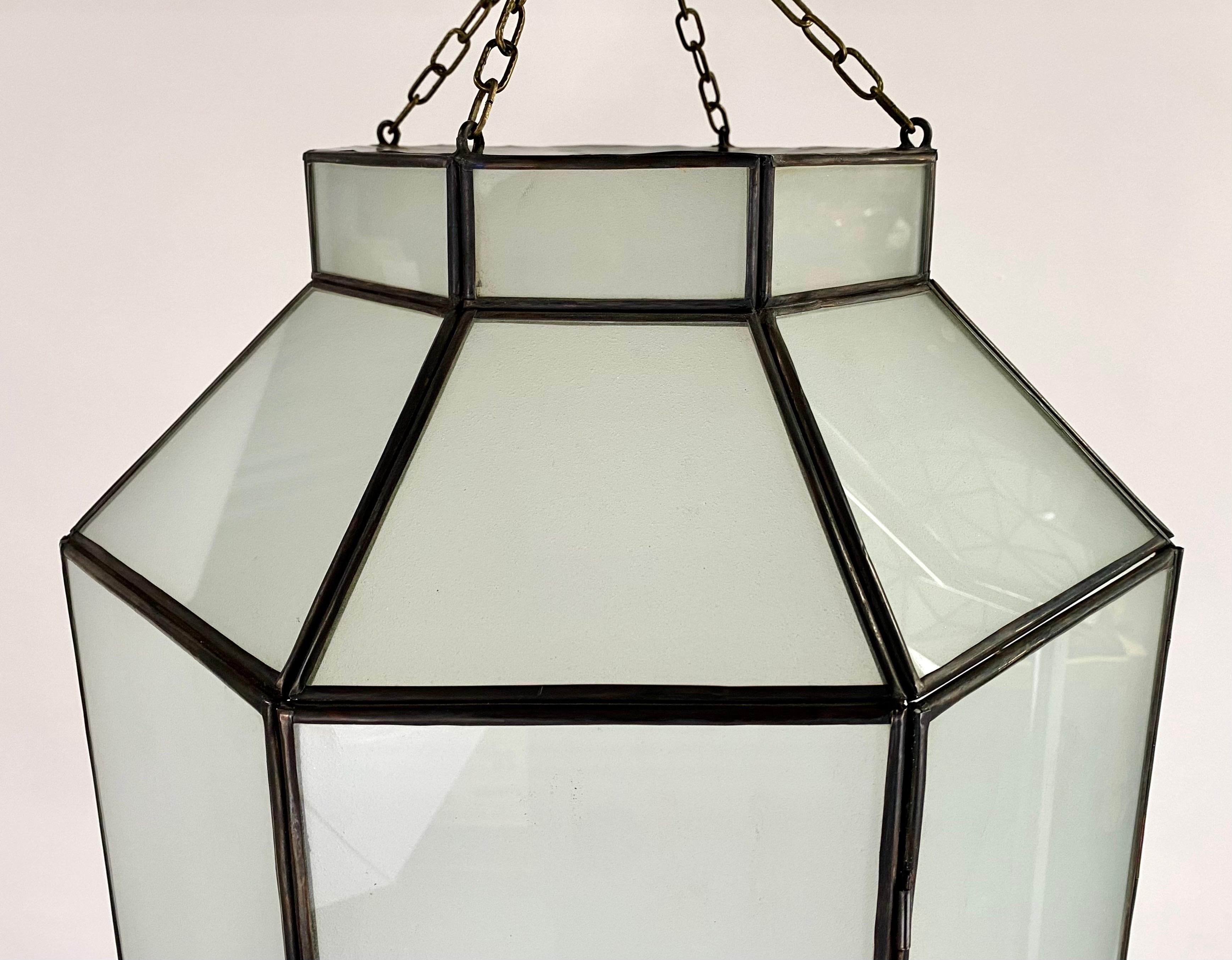 An Art Deco style chandelier, pendant or lantern. Featuring a stylish octagonal shape, the chandelier or pendant is finely hand-made of individual sandblasted frosted milk glass panels and patinated bronze frame. The octagonal shaped pendant has a