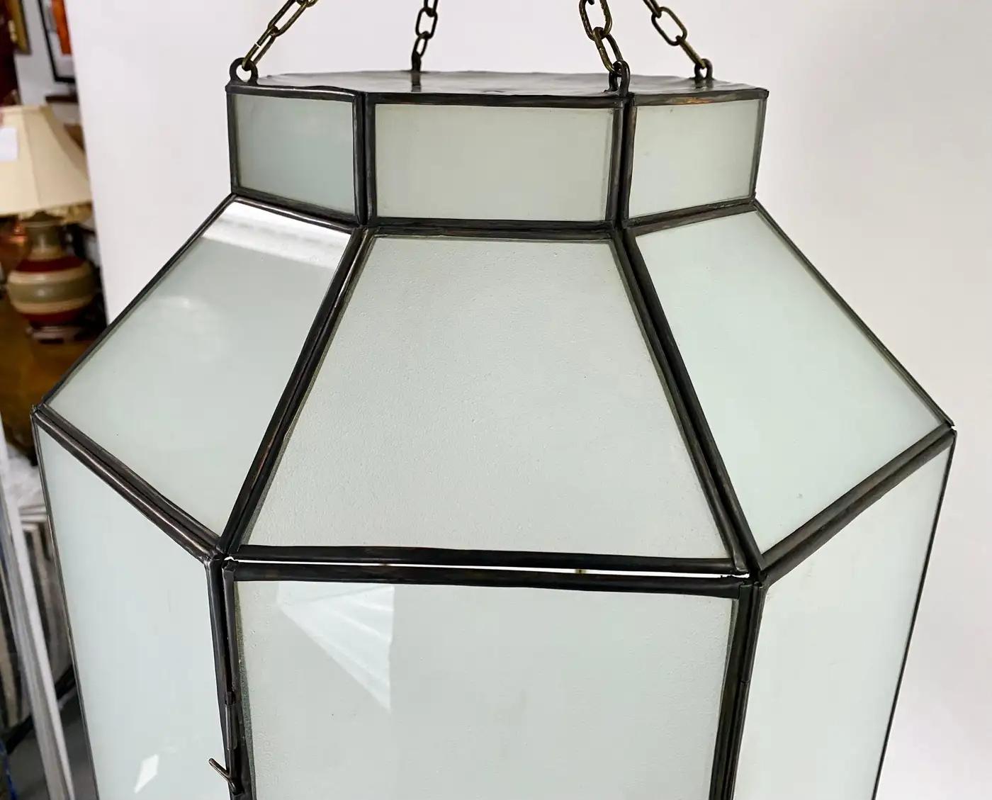 An Art Deco style chandelier, pendant or lantern. Featuring a stylish octagonal shape, the chandelier or pendant is finely hand-made of individual sandblasted frosted milk glass panels and patinated bronze frame. The octagonal shaped pendant has a