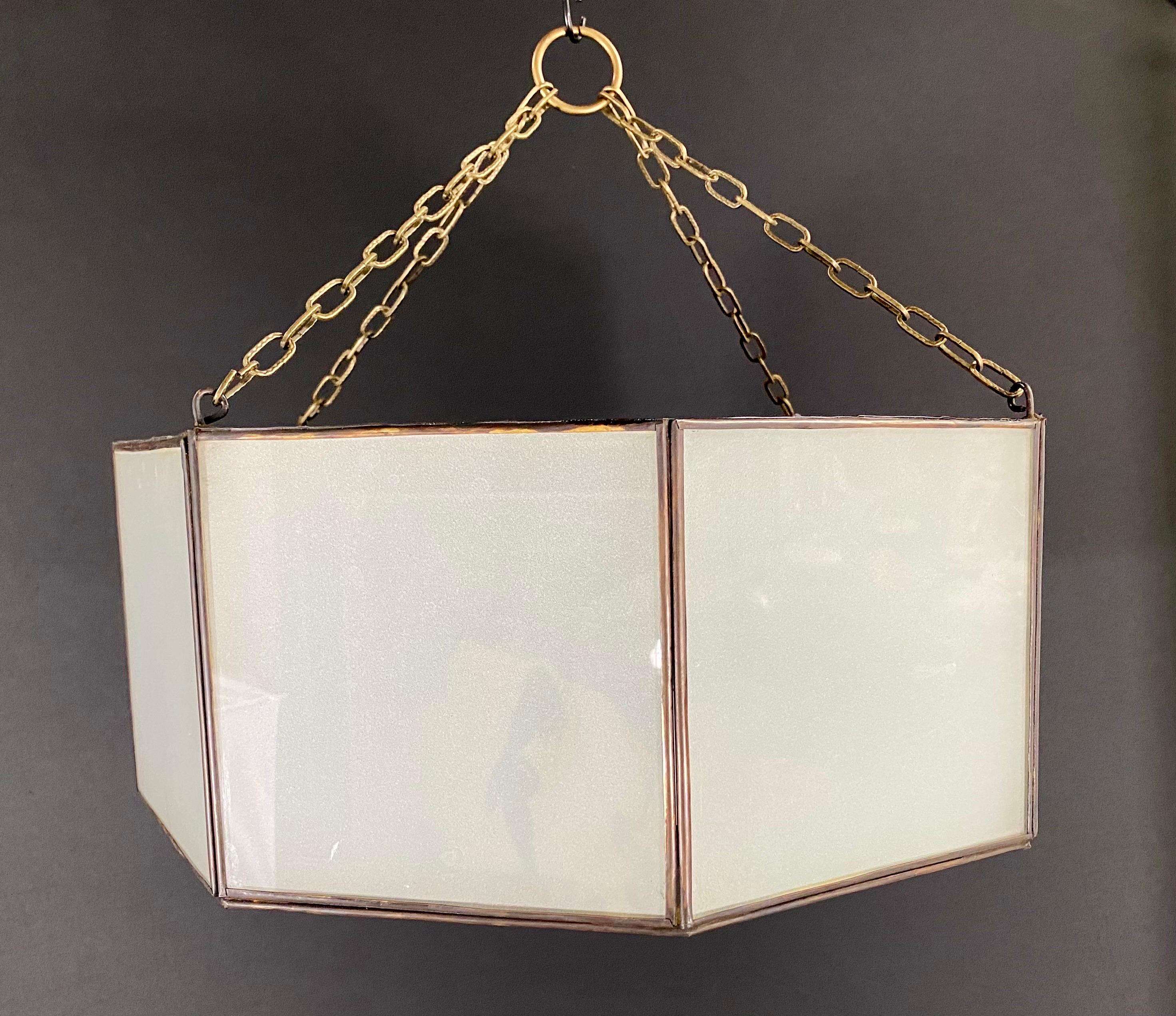 A pair of Art Deco style pendants, lanterns or flush mount. Featuring a stylish octagon shape, the pendants are finely handmade of individual sandblasted frosted milk glass panels and patinated bronze frame. The octagonal shaped pendants have a