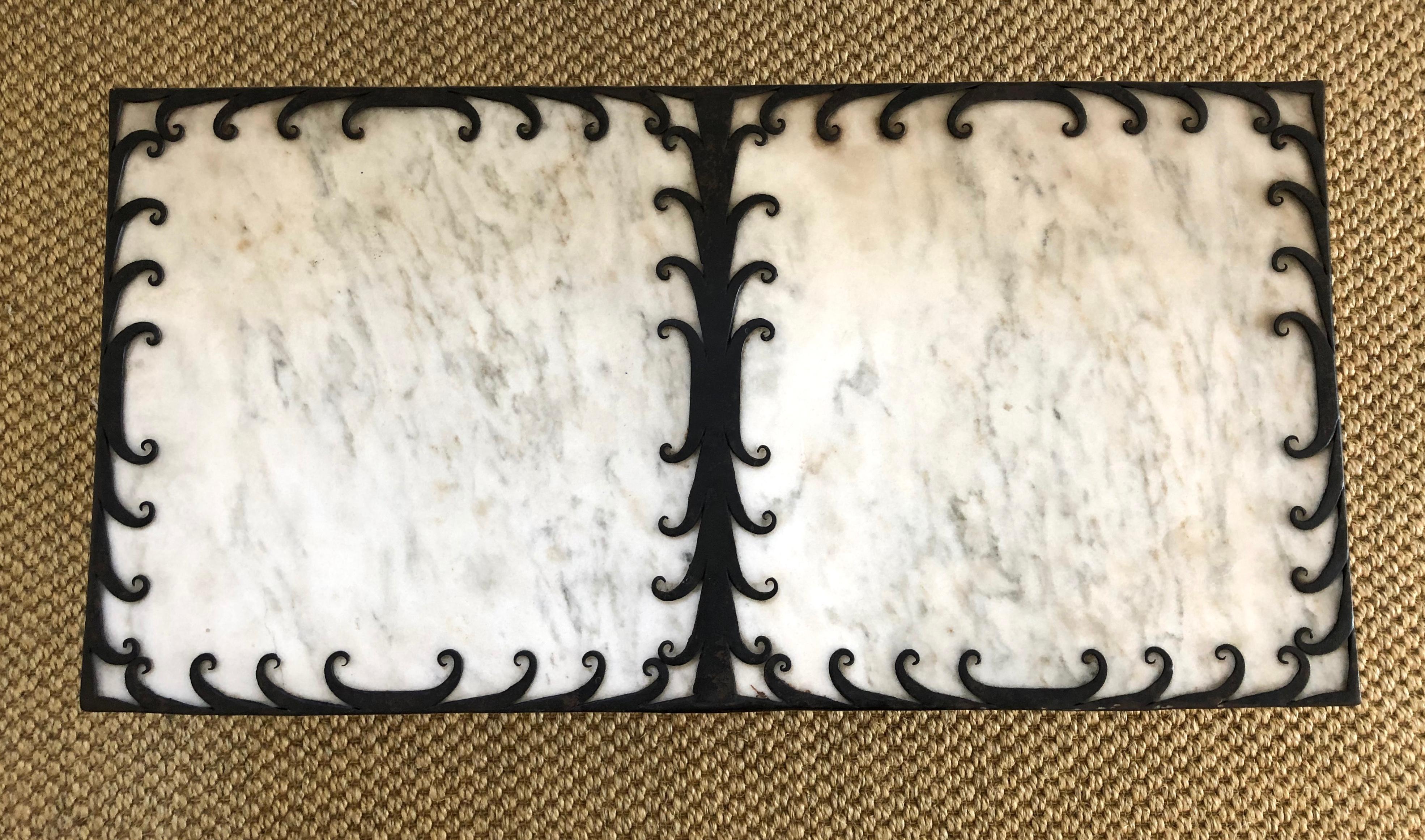 An Art Deco style rectangular coffee, or cocktail, table, the Carrara marble top within a wrought iron frame, decorated with finely modeled wrought iron scrolls around the perimeter and dividing the center, raised on wrought iron scrolled legs