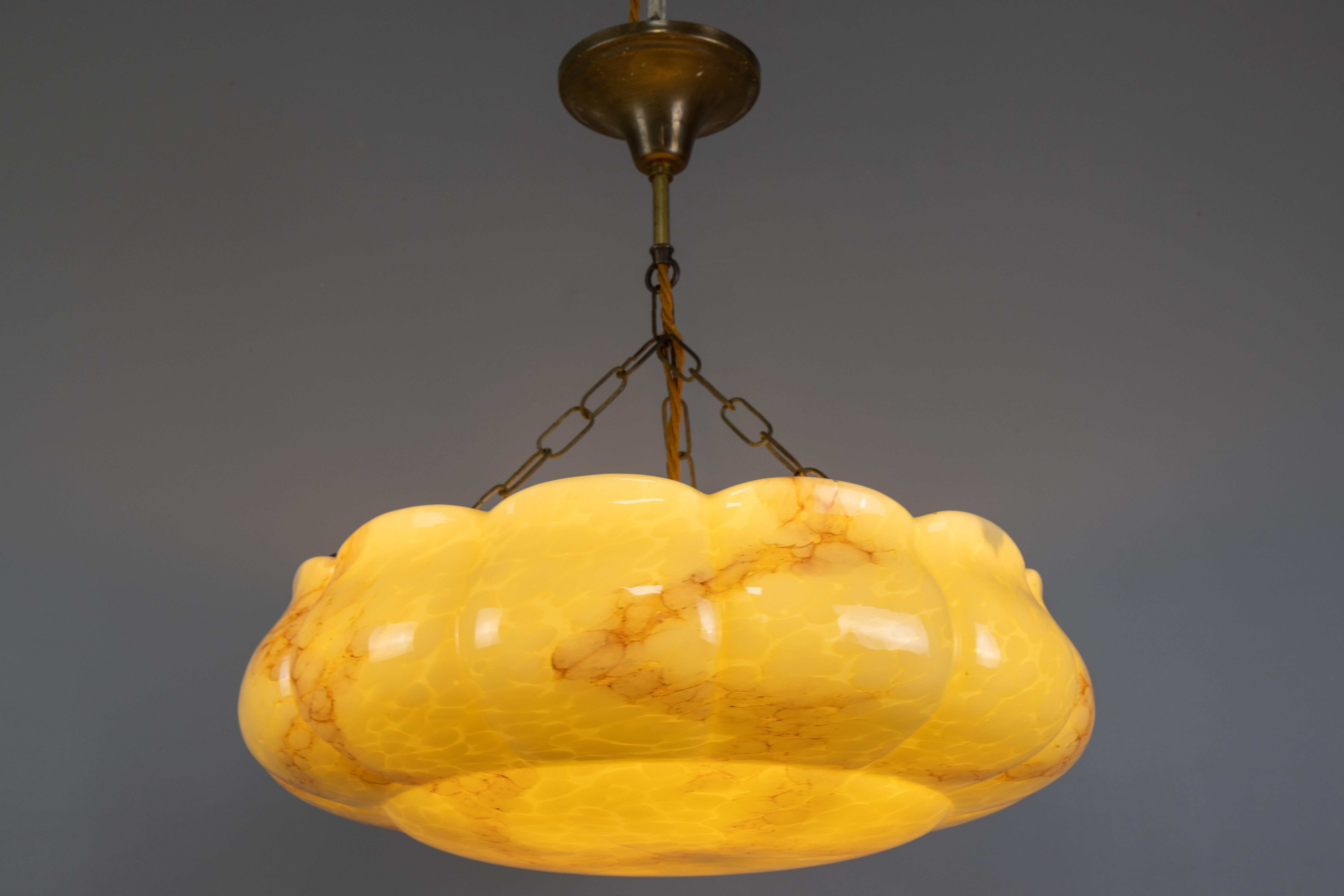 Art Deco-style yellow and beige marbled glass pendant light, Germany, circa the 1950s.

This elegant pendant light features a beautifully scalloped glass shade in a striking yellow and beige marbled pattern, typical of the refined aesthetics of the