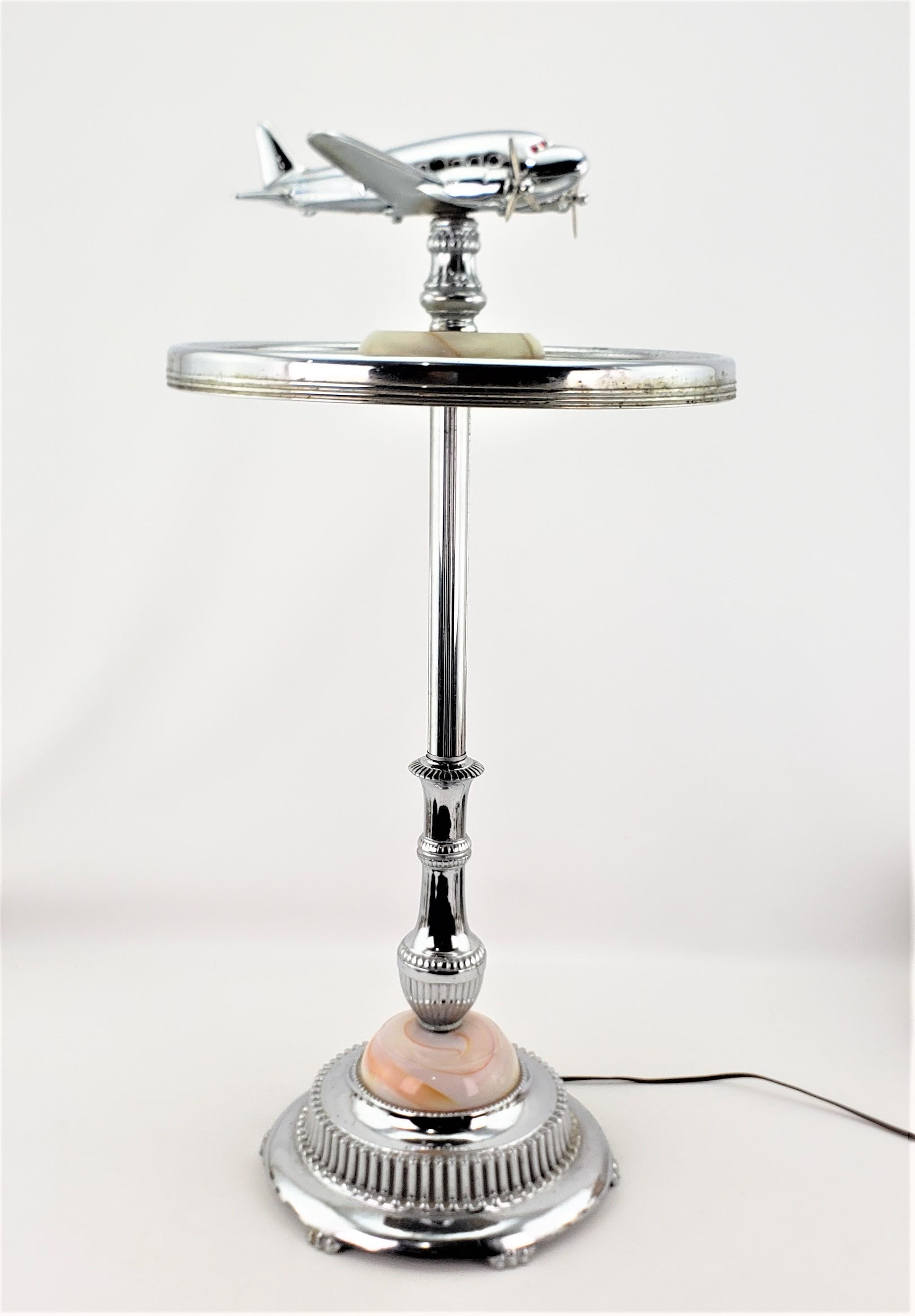 This very unique lighted smoker's stand is unsigned, but presumed to have been made in North America, likely the United States, in approximately 1950 in an Art Deco style. This smoker's stand is done in chromed metal with a streamlined and stylized