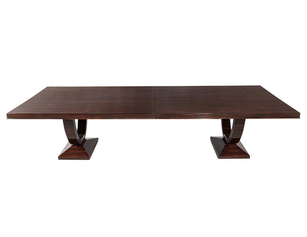 This stunning Art Deco dining table, crafted in France by the renowned Philippe Hurel, is a true statement piece. The exquisite Macassar ebony wood is showcased in a high-gloss polished finish, highlighting its rich, swirling grain. The table rests