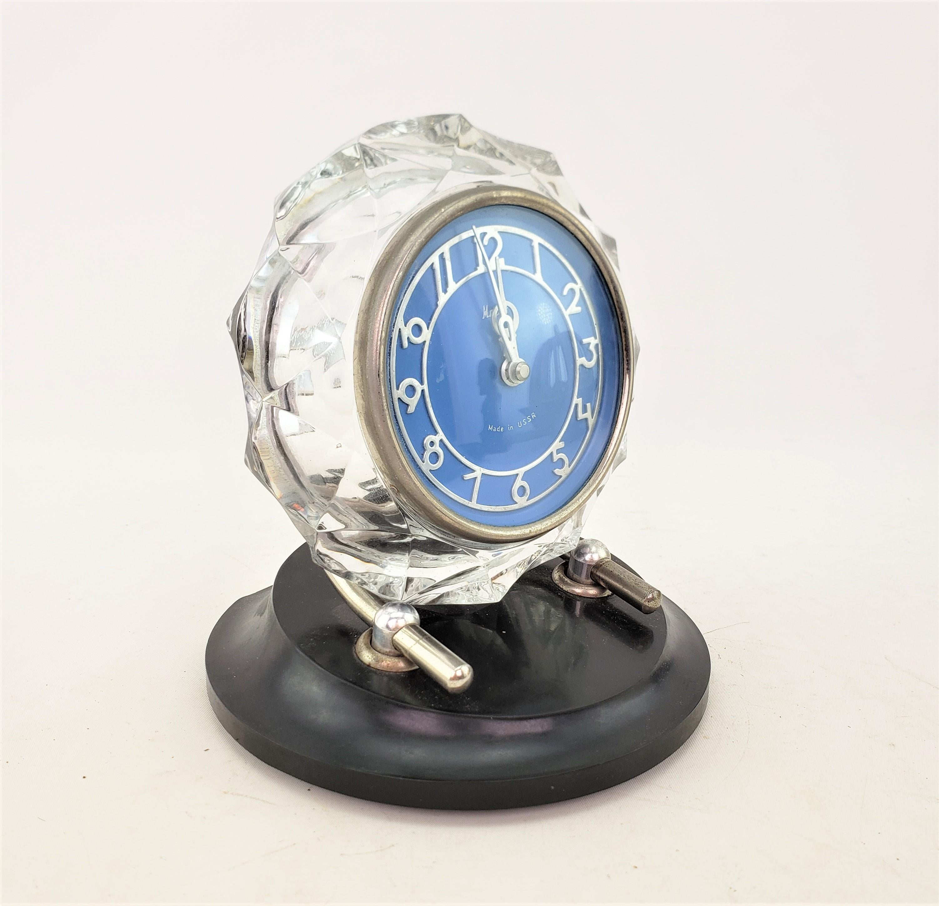 This desk or table clock was made by Majak Mayak of the former U.S.S.R. in approximately 1920 and done in the period Art Deco style. The clock face and movement is composed of metal with a thick and heavy faceted crystal case with steel supports on