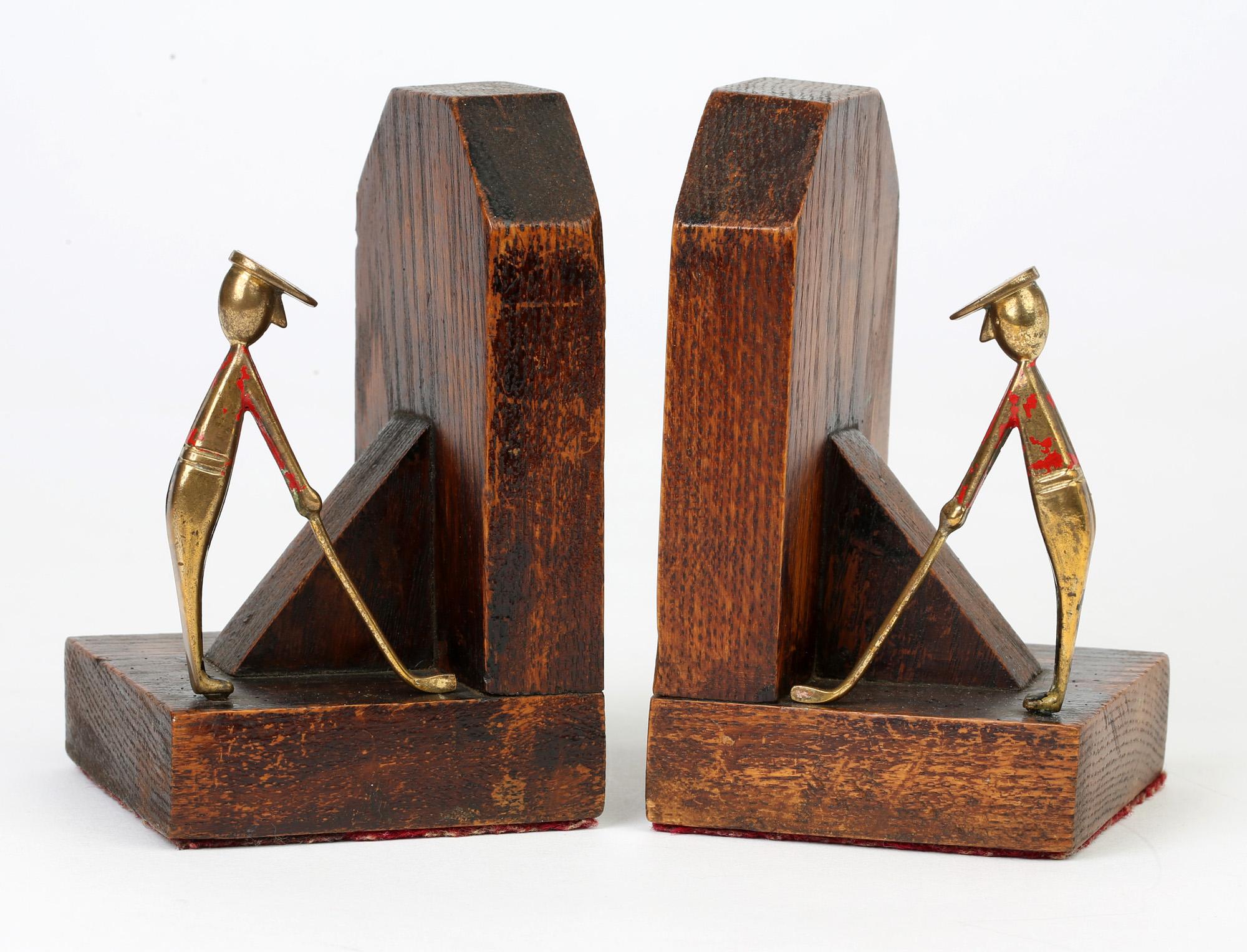 Stylish pair Art Deco stained wooden bookends mounted with enameled brass golfing figures dating from circa 1925. These stylish bookends are made up of two carved blocks of wood joined by an angled central strut and each with a Hagenauer style brass