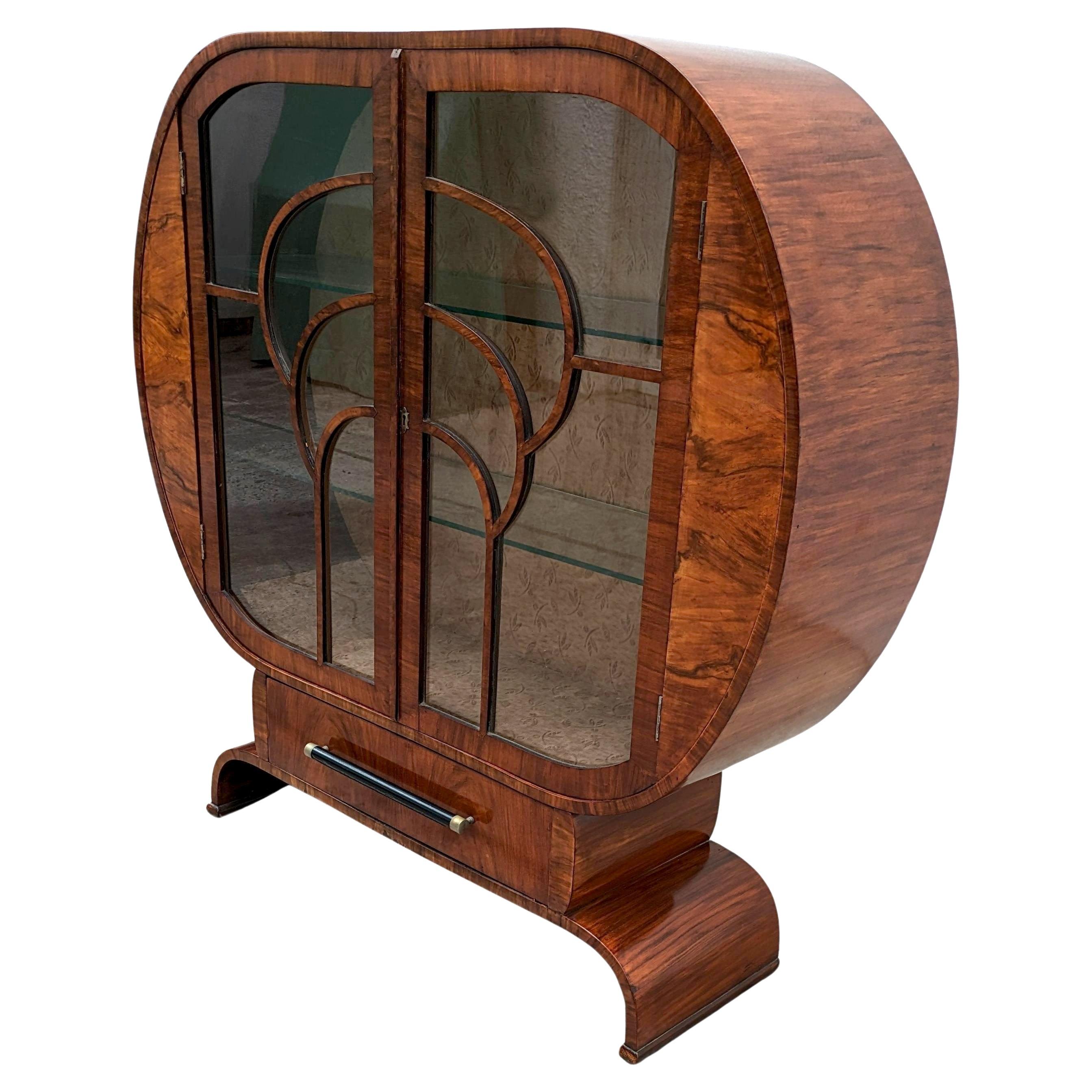 Superbe vitrine Art déco des années 1930 en noyer à la forme farfelue. Les placages de ce meuble sont magnifiques et légèrement plus détaillés que la moyenne. Forme très inhabituelle et très représentative de cette grande époque révolue. Il y a deux