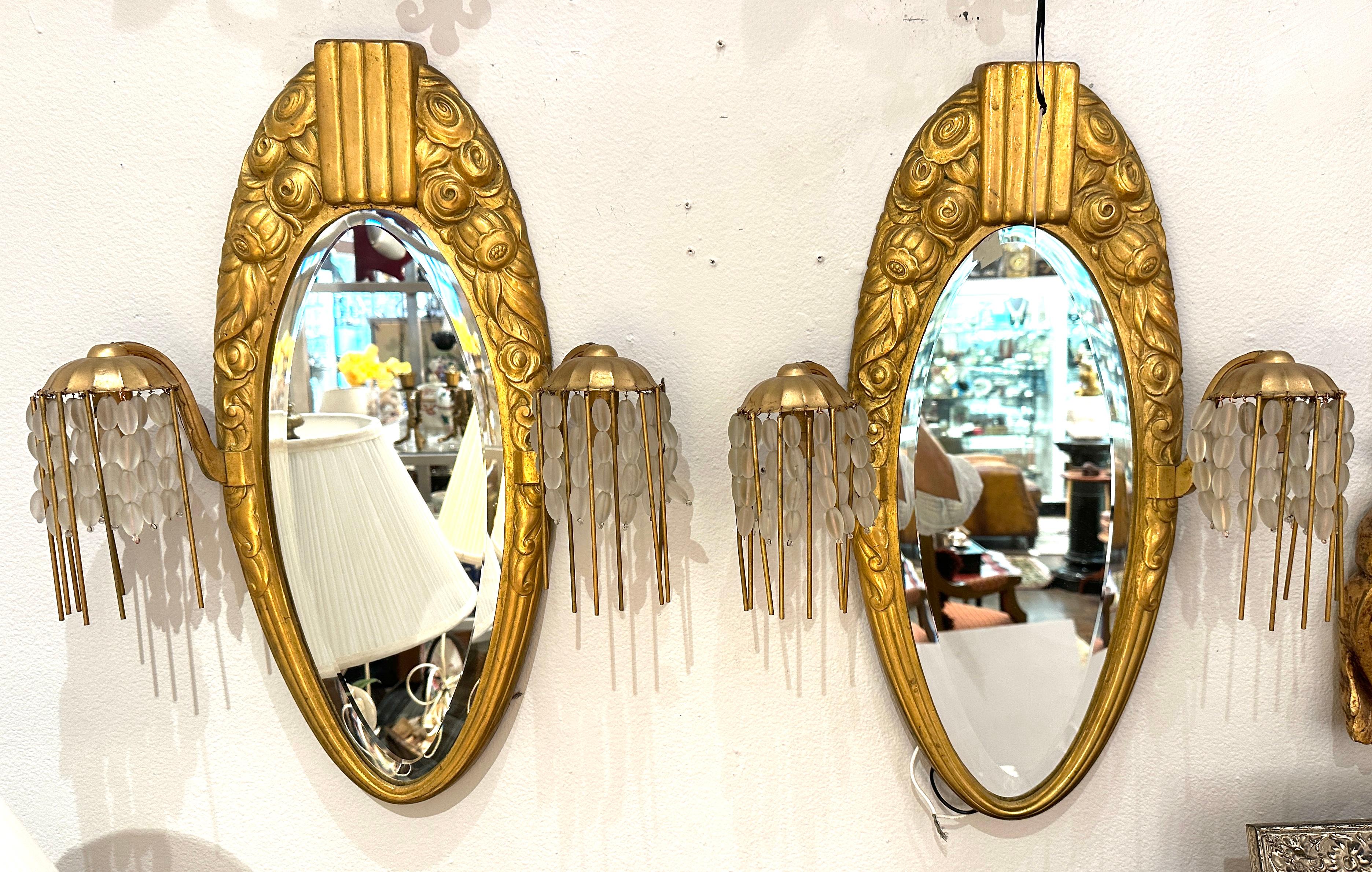 1920s Sue et Mare.  Exceptionally beautiful Gilt bronze oval mirror flanked on sides with glass bead covered down lights.  
Created by French designers Sue et Mare.  
Oval bevel mirrors have been newly replaced, but the original mirrors can be