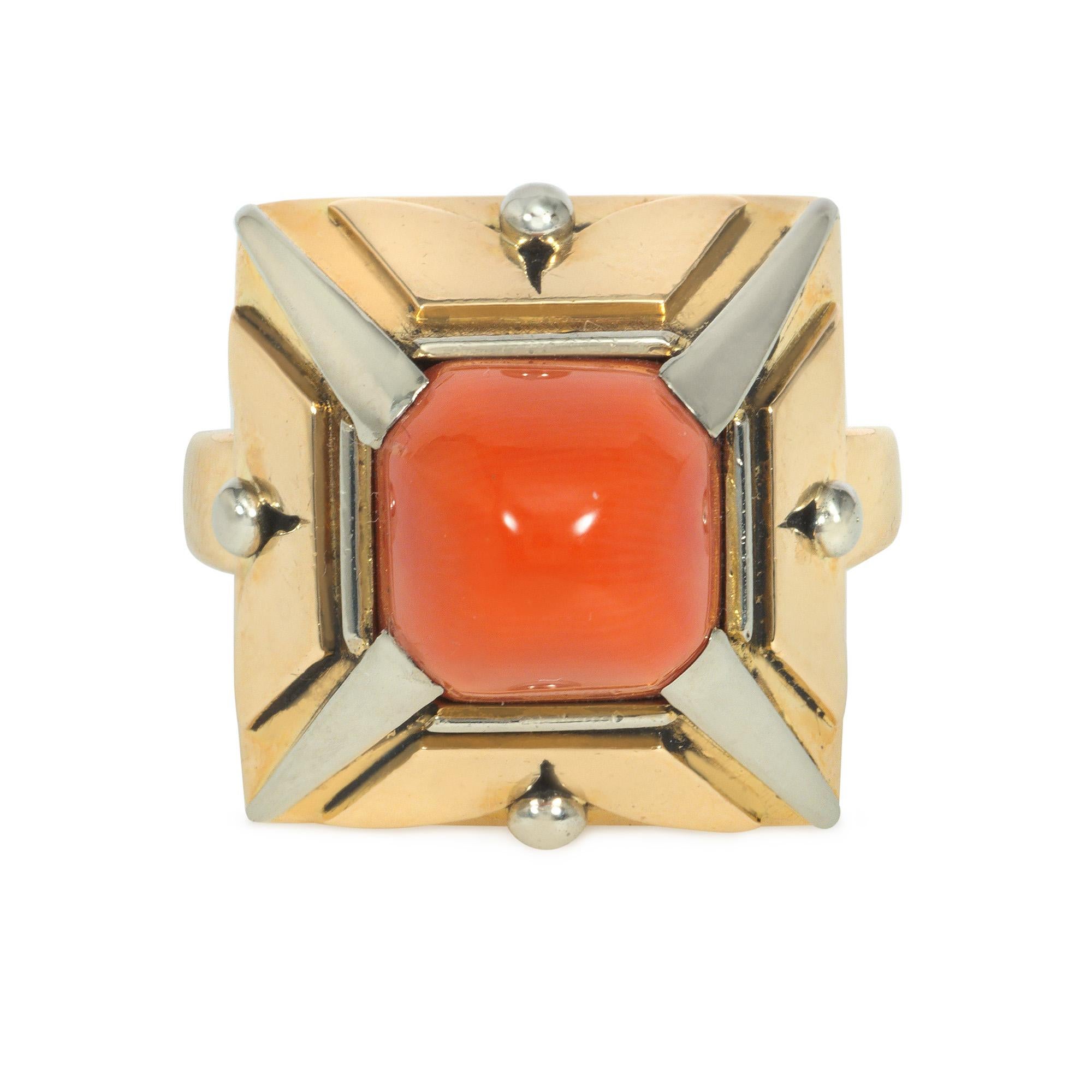 An Art Deco coral, platinum, and gold ring of pyramidal design, centered by a sugarloaf coral with pierced gold sides separated by tapering platinum bars, in 18k.  Face-up dimensions approximately 0.75