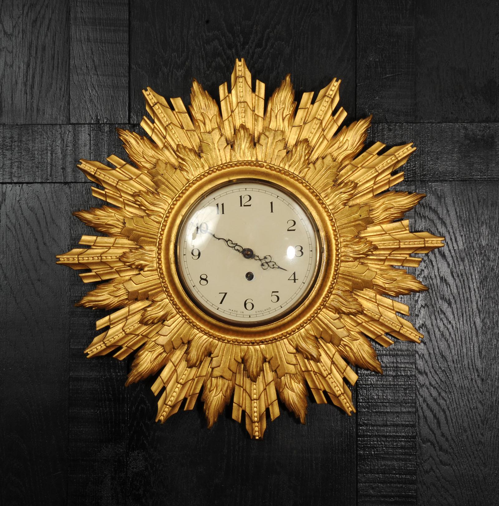 A large and spectacular Art Deco sunburst wall clock by the Coventry Astral clock company. Beautiful gilt wood in nice original condition with some marks and fading that only add to its decorative appeal. The dial is painted metal with a convex