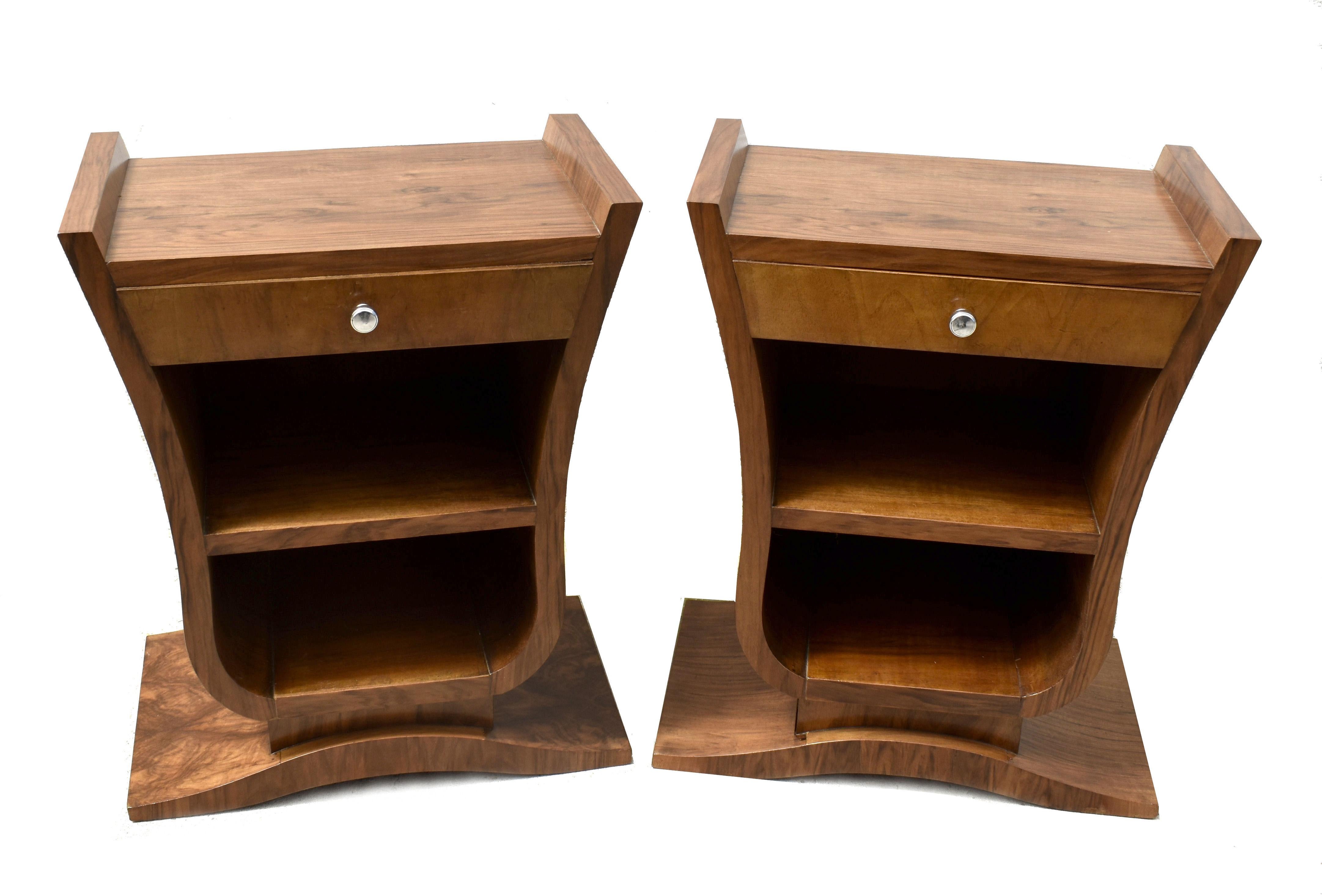 An Art Deco pair of curvaceous French bedside tables in figured walnut are up for your consideration. Made in the 1930's and originating from France these boast the very desirable u base on a triangular plinth, an iconic shape not to be mistaken for