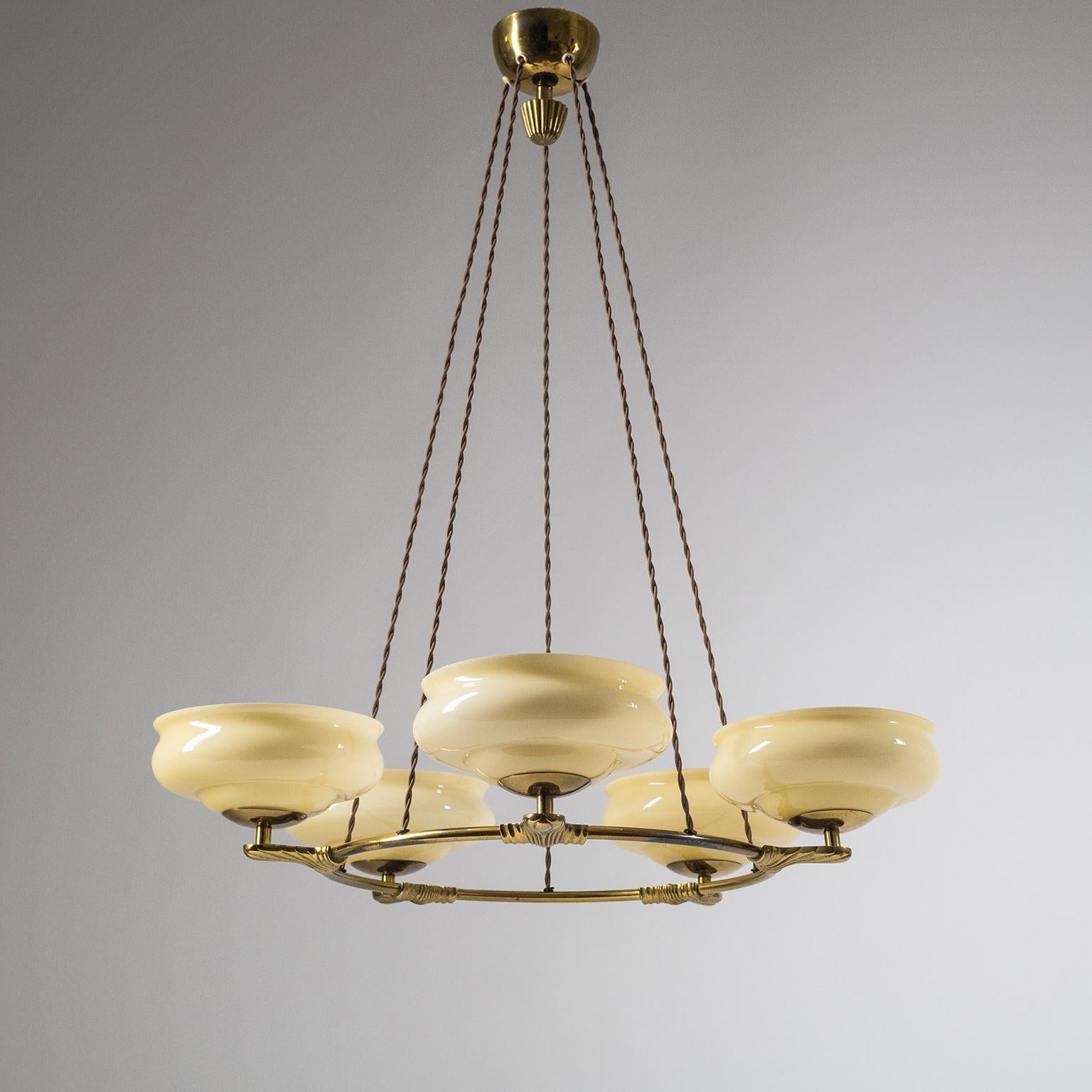 Rare Art Deco suspension chandelier, from the 1930s. Brass ring with five cast brass arms, each with a blown glass diffuser. The glasses are triple layered with sand tinted glass on the in- and outside and a white central layer for an overall cream