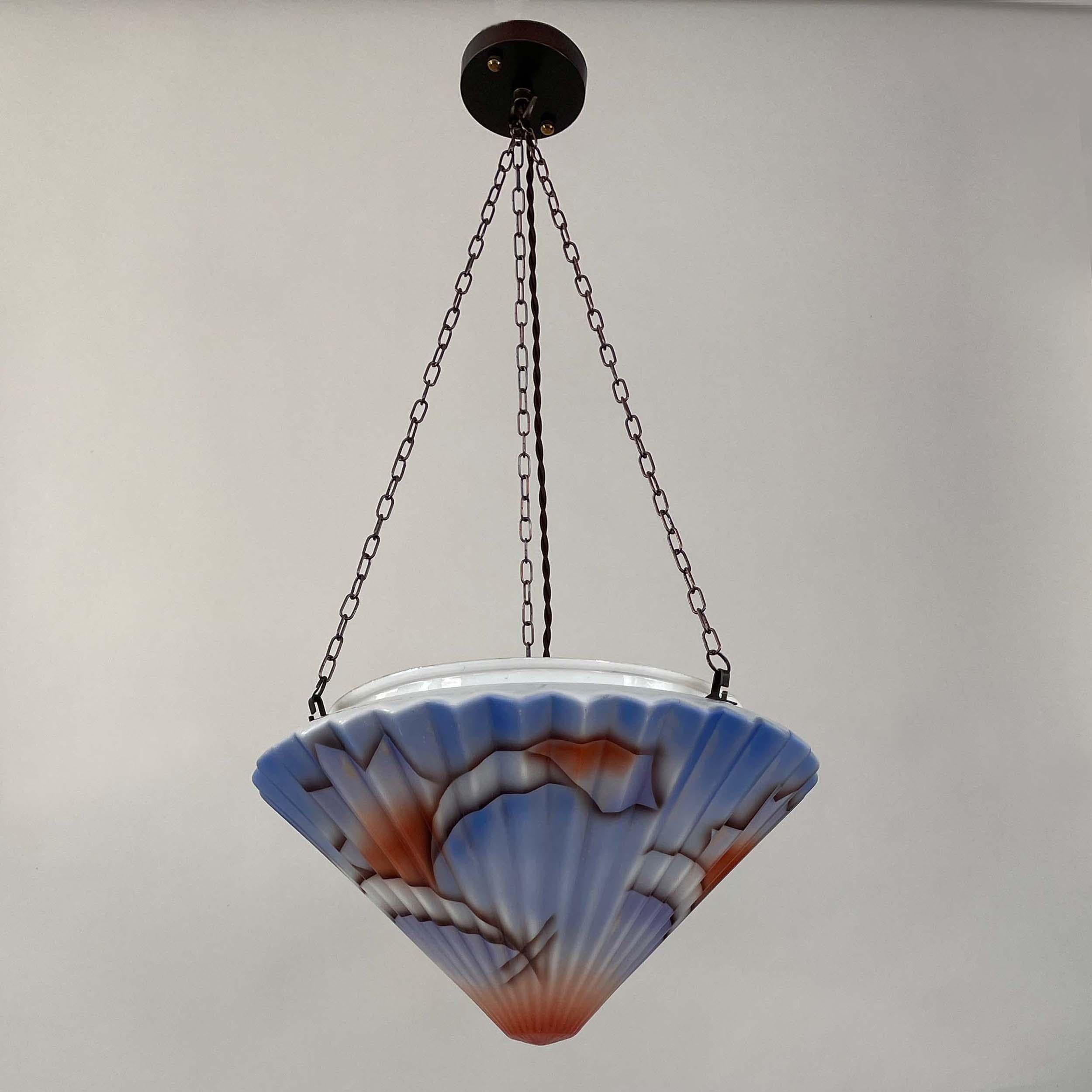 This rare Bauhaus inspired pendant was designed and manufactured in Germany in the late 1920s to early 1930s. It features an enameled glass lampshade and bronzed brass hardware. The colorful glass diffuser with typical splash decor pattern. 

Good