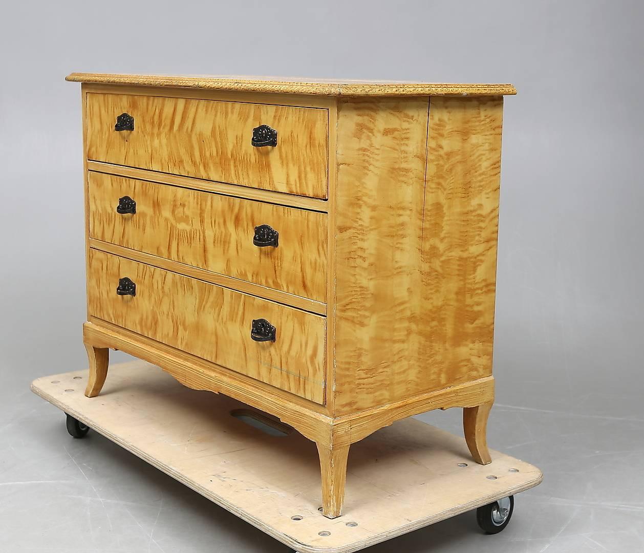 Early 20th century Classic Art Deco Biedermeier style flame golden birch veneer chest of drawers commode with three drawers and carved plinth. Classic honey color French polish.

It has lovely curved feet and ring pull handles.

Beautiful and