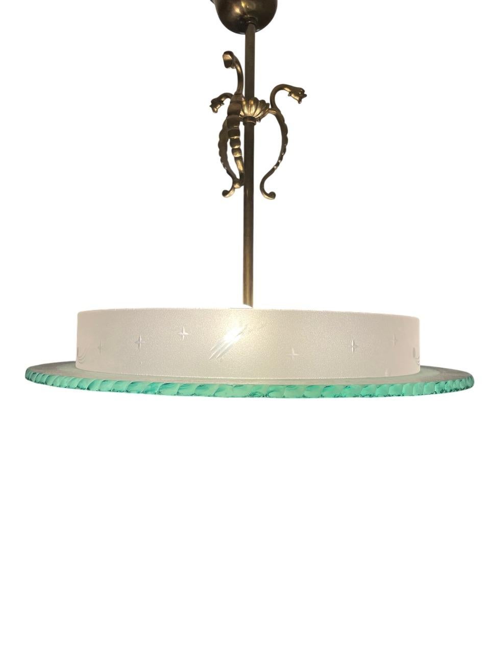 Un'impressionante plafoniera svedese Art Deco degli anni '30 con un paralume in vetro fuso con motivi floreali incisi e un bordo delicatamente smerlato. Il vetro ha una presenza sostanziale e scultorea, abbinato a uno stelo in ottone patinato ornato