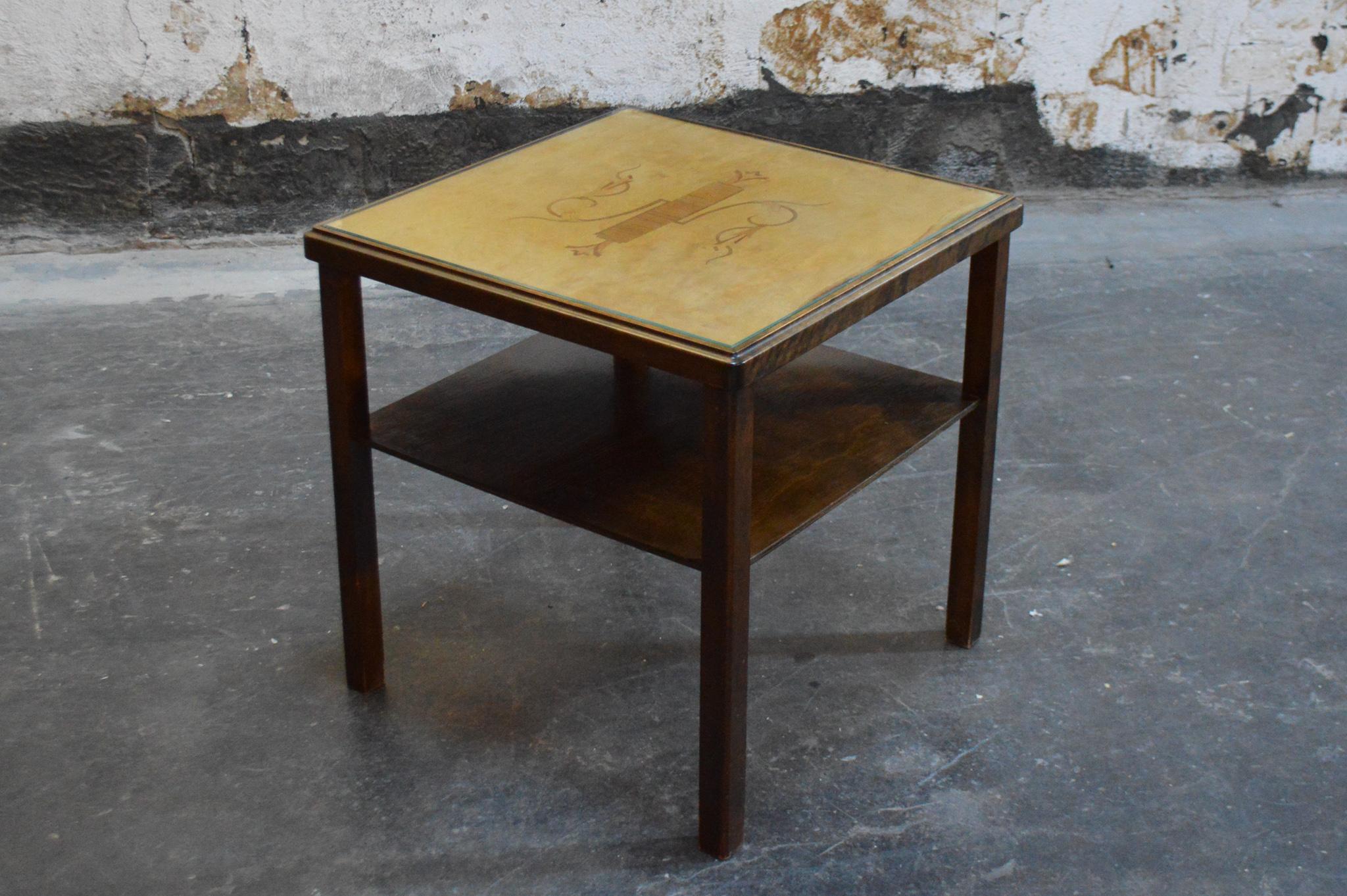 Swedish Deco end or side table with a golden birch top with elm inlay and a dark flame birch base. The table top is paneled and inlaid with intarsia of elm and jacaranda with a glass top and it has a dark flame birch shelf. It is the perfect size