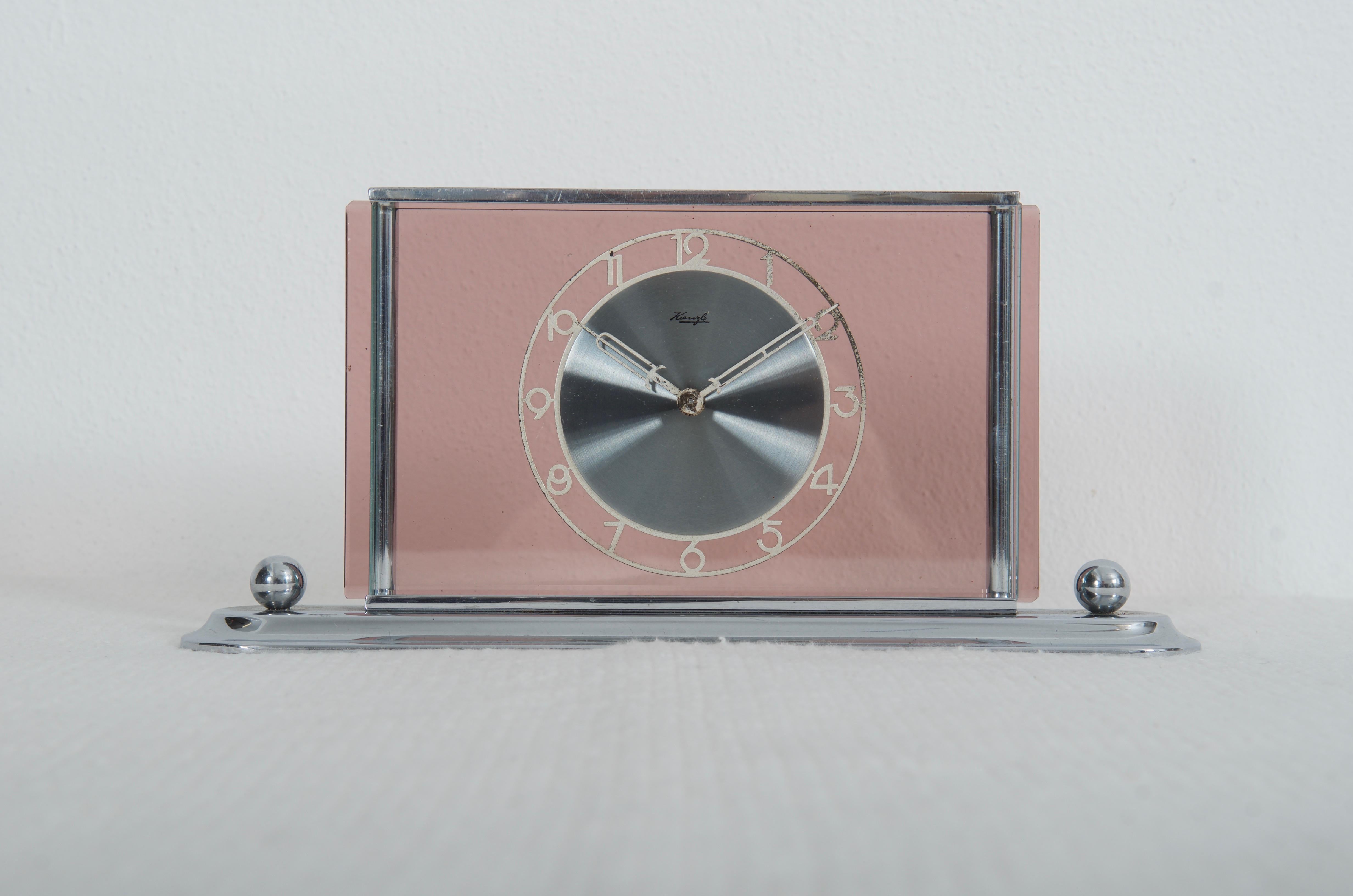 Messingrahmen, vernickeltes Ziffernblatt aus poliertem Stahl, befestigt auf rosafarbenem Glas, hergestellt von Kienzl in den späten 1930er Jahren. Ausgestattet mit einem mechanischen Uhrwerk. Auf Wunsch kann auf eine Batterie umgebaut werden.
 